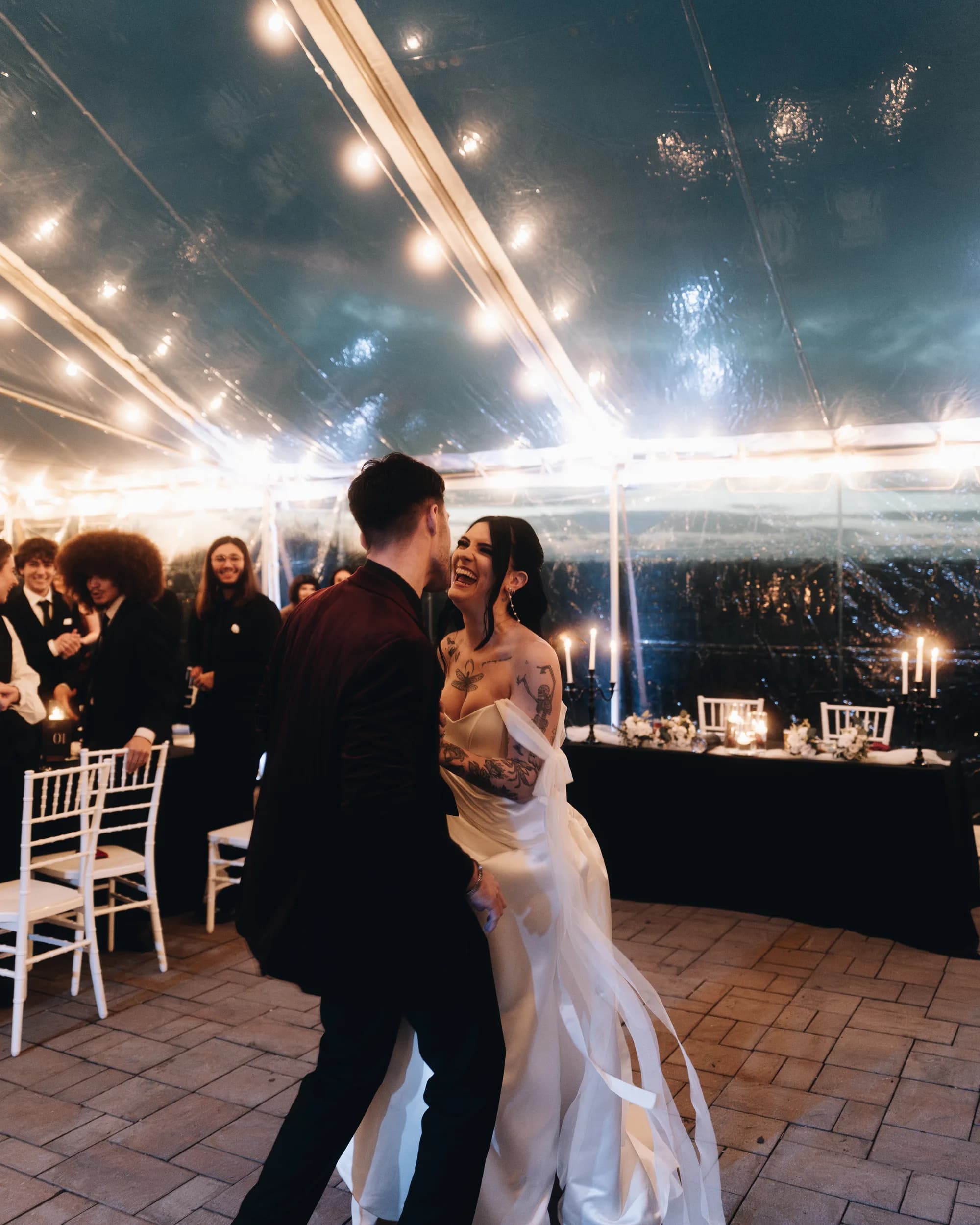 Bride laughing joyfully during first dance under string lights in Rixey Manor's tent reception space