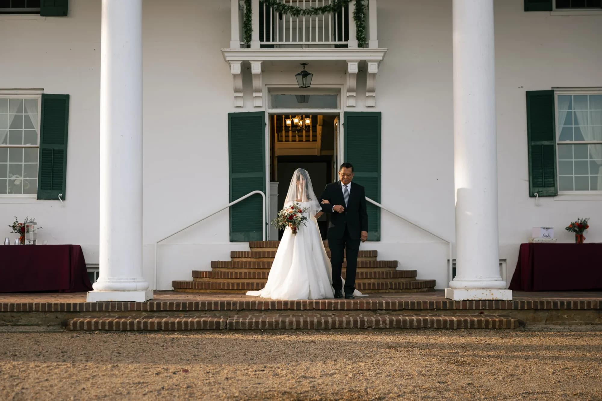 Bride and escort descend brick steps of Rixey Manor's white-columned antebellum facade before ceremony