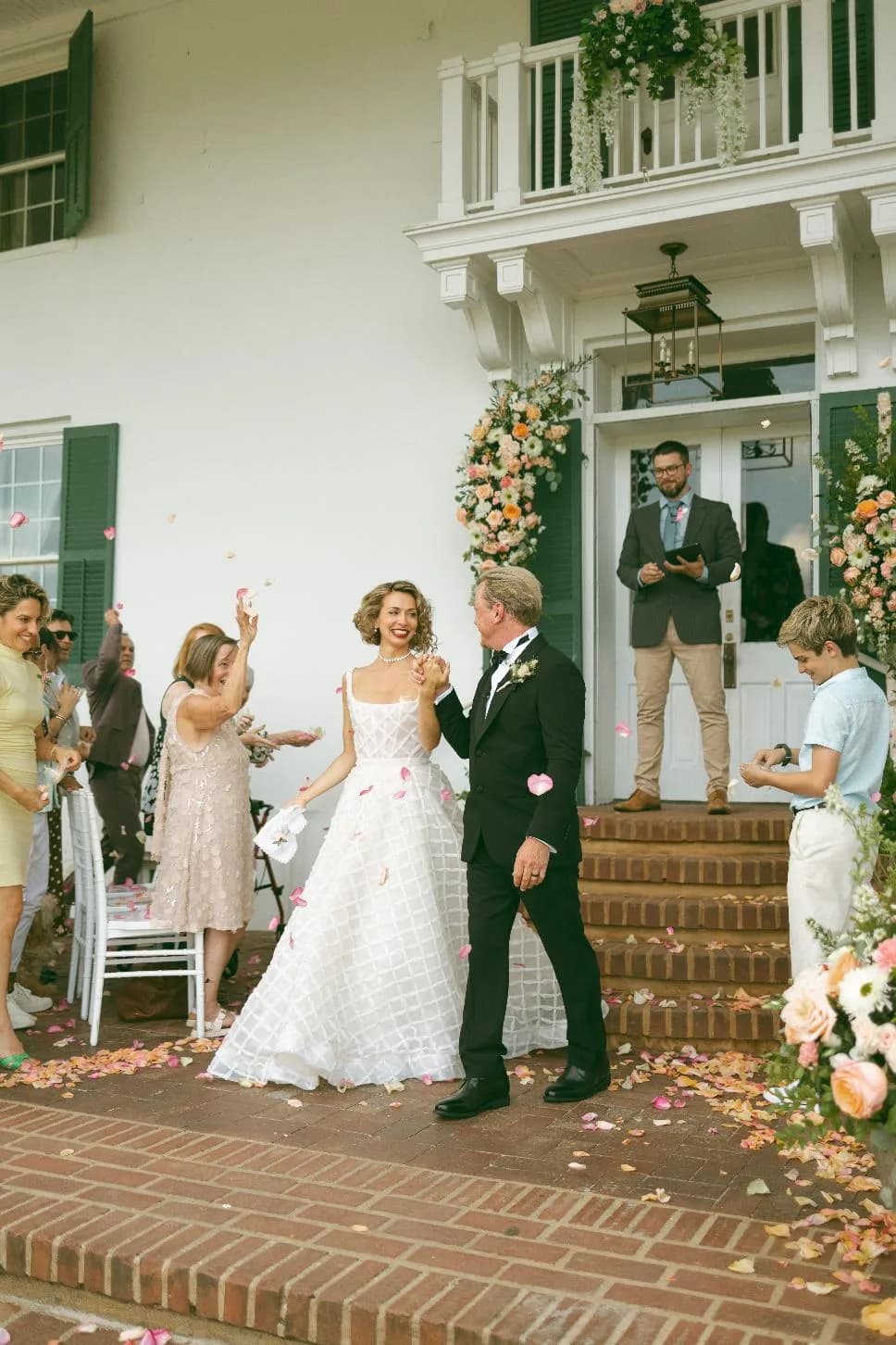 Bride and groom exit Rixey Manor's historic white columned entrance as guests shower them with rose petals