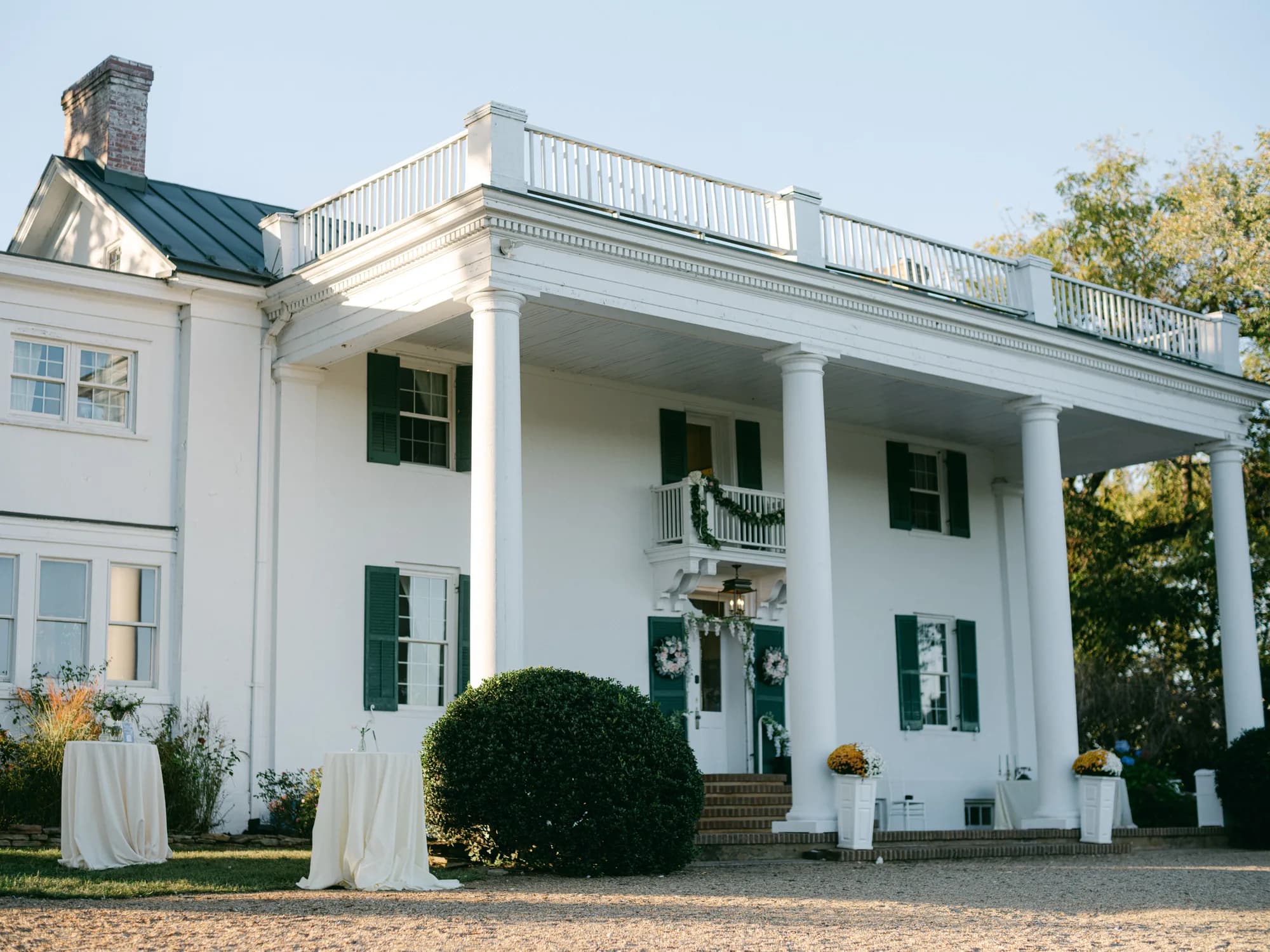 White columned facade of Rixey Manor decorated with wreaths and florals on a clear autumn day