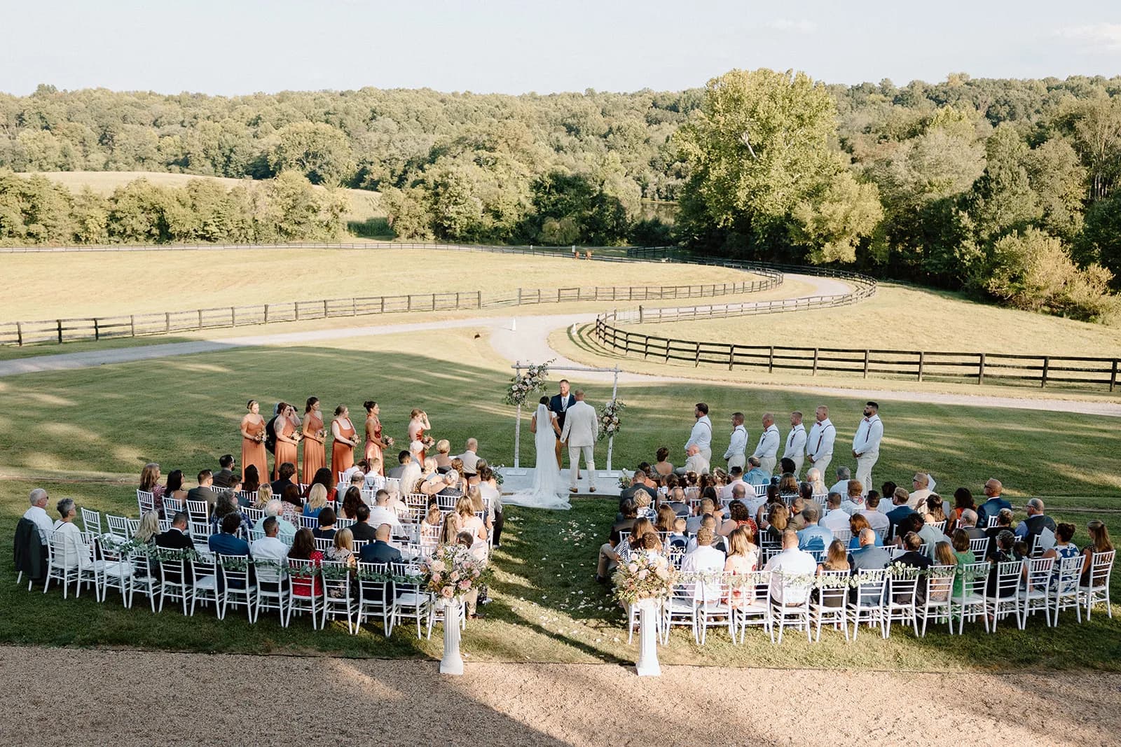 Outdoor wedding ceremony at Rixey Manor, rolling hills and fenced pastures behind the guests