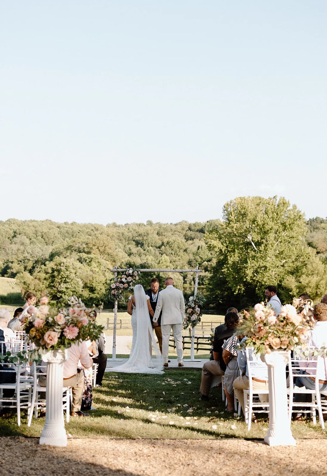 Couple exchanging vows on the front steps of Rixey Manor with guests seated on the forecourt and lush lawn