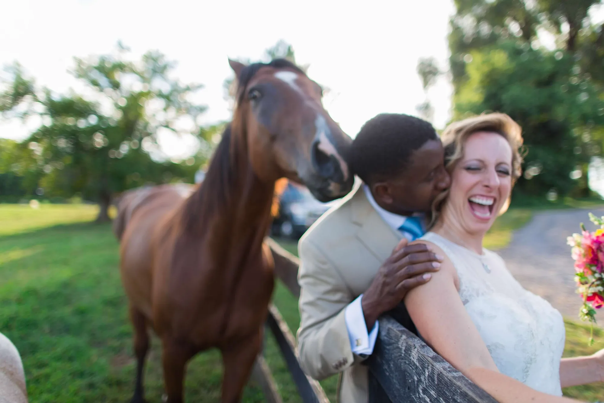 Bride and groom pose with a horse at a rural Virginia wedding venue on a sunny day.