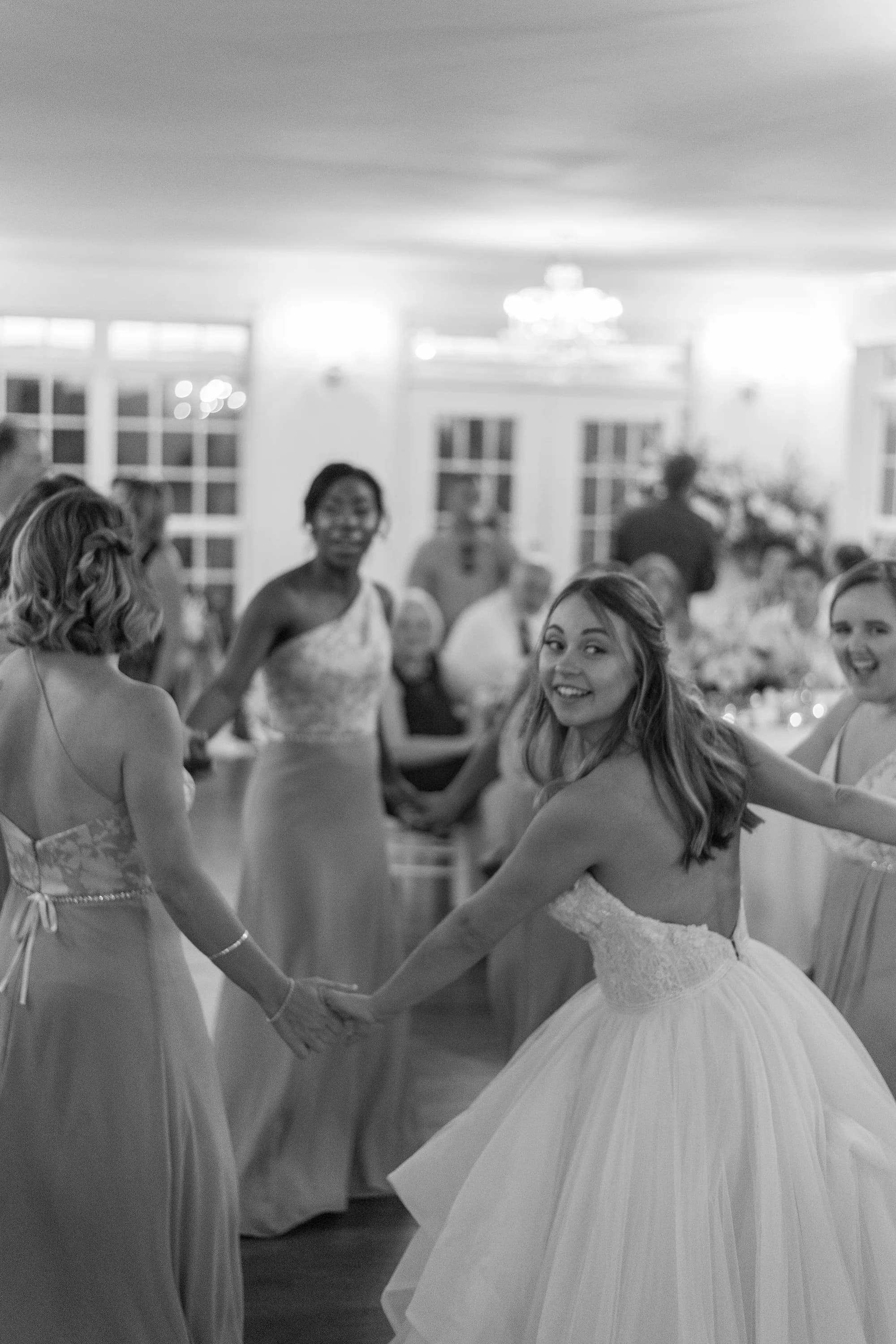 Bride laughs and spins with bridesmaids on the dance floor during Rixey Manor wedding reception