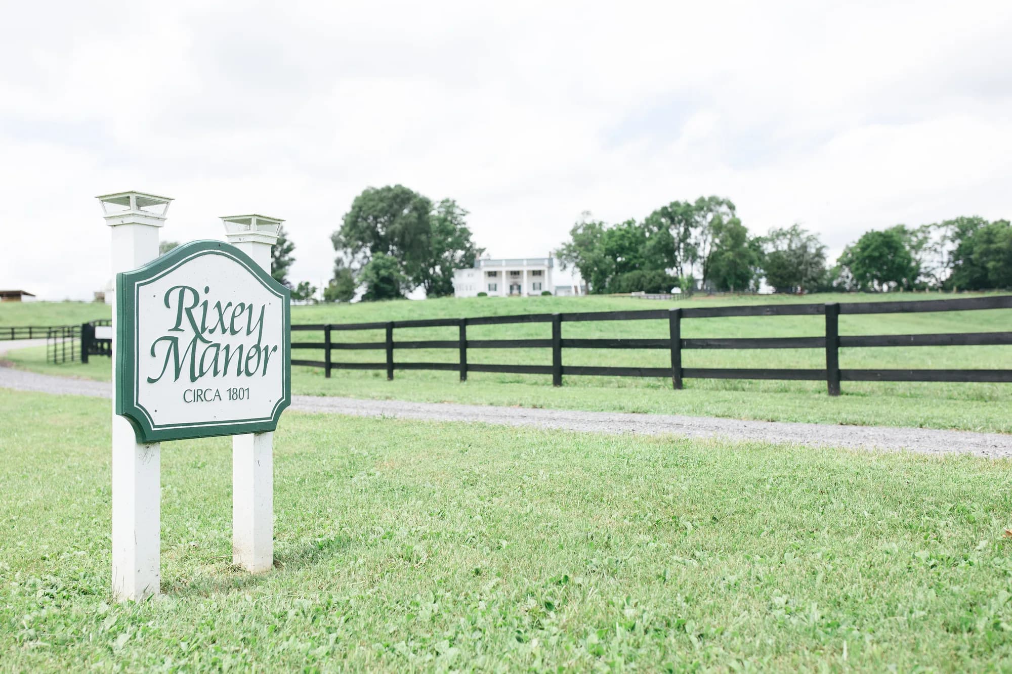 Rixey Manor entrance sign with white fencing and manor house visible across green pasture