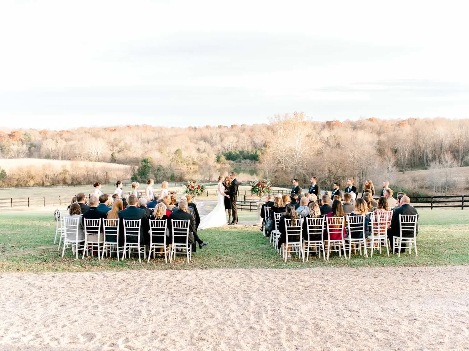 Outdoor fall wedding ceremony on Rixey Manor's pastoral grounds with guests seated in Chiavari chairs