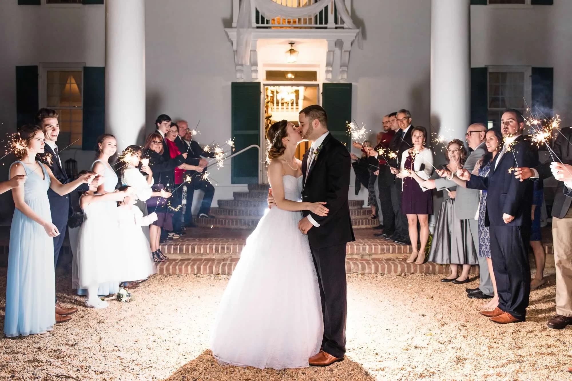Bride and groom kiss during sparkler sendoff on Rixey Manor's grand front steps at night