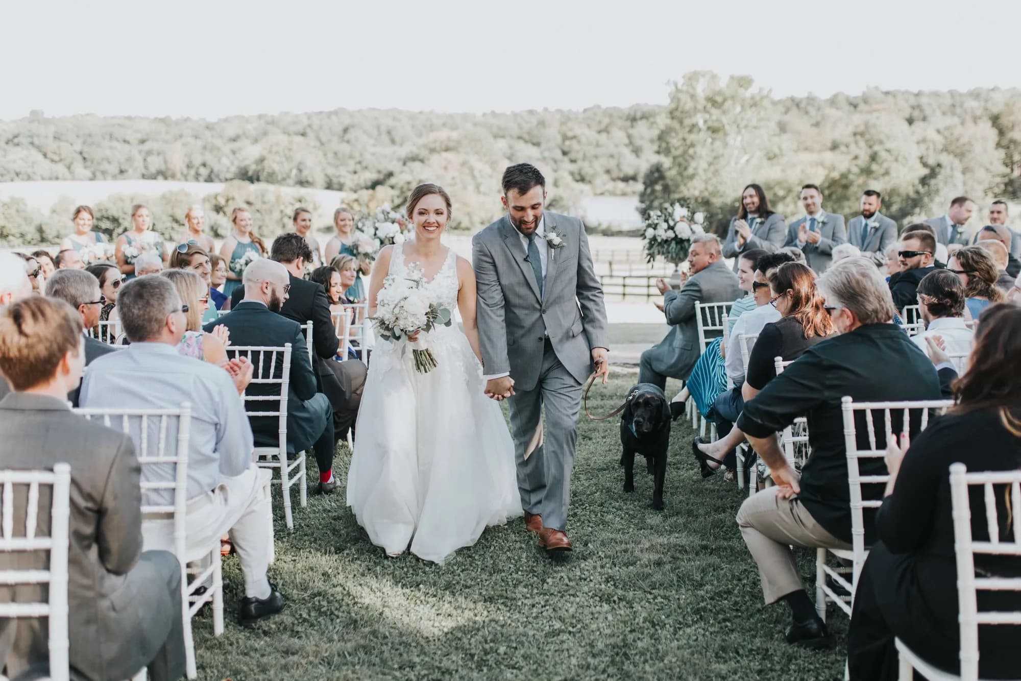 Beaming couple walks back down the aisle after marrying at Rixey Manor's outdoor ceremony on lush green grounds