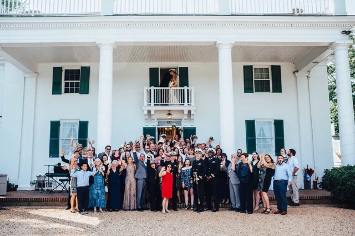 Wedding guests cheer as couple appears on Rixey Manor balcony of the white columned antebellum mansion