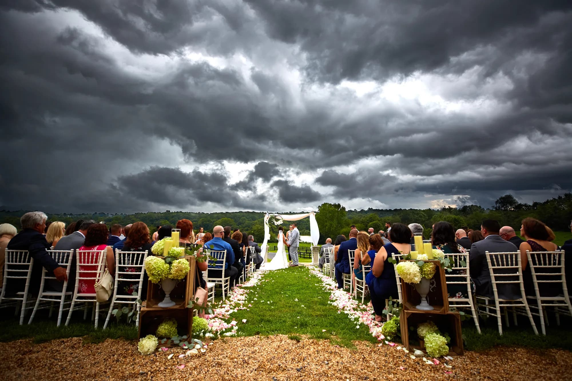 Couple exchanges vows at outdoor altar as dramatic storm clouds roll over Rixey Manor's sweeping ceremony grounds