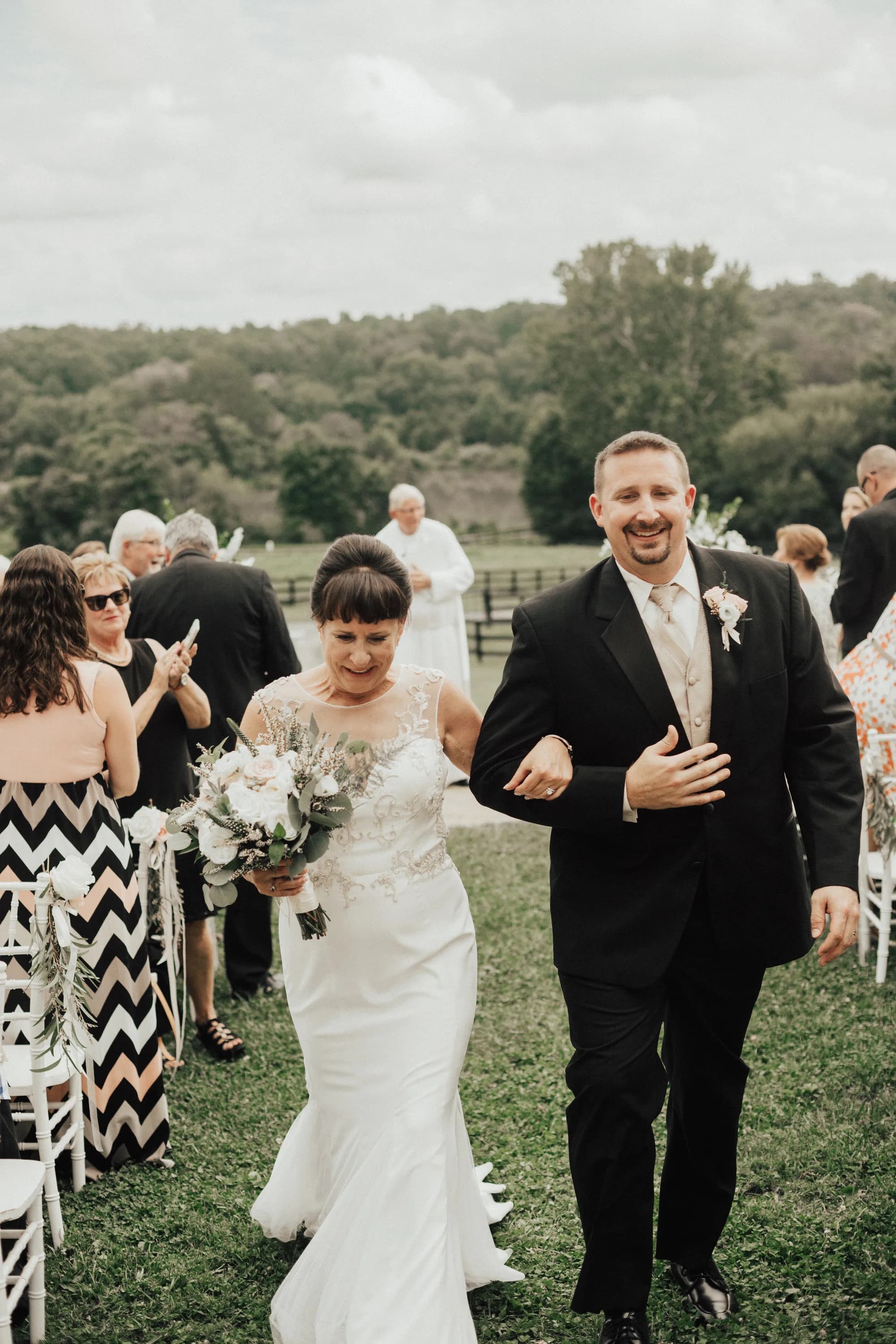 Newlyweds walk back down the aisle at Rixey Manor outdoor ceremony, groom beaming, lush Virginia grounds behind them