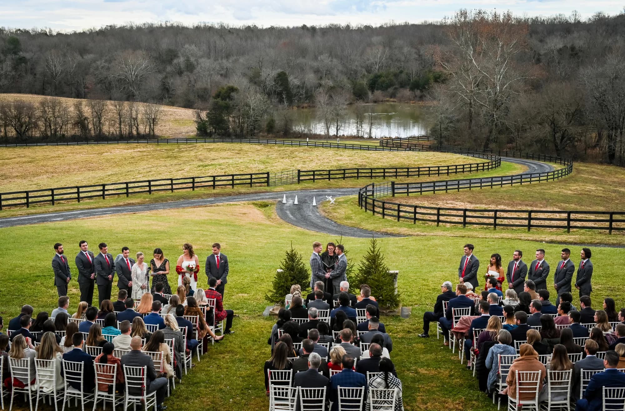 Aerial view of outdoor wedding ceremony at Rixey Manor with rolling hills, pond, and winding fence-lined drive