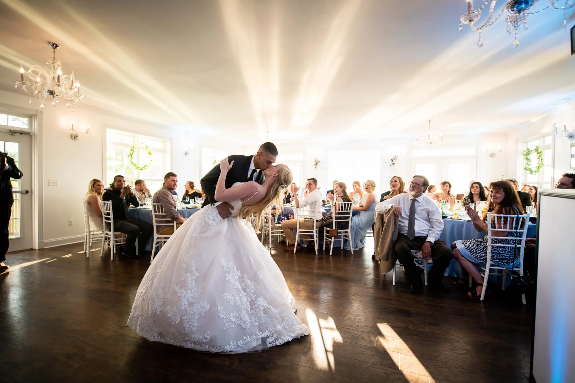 Bride and groom share a romantic dip kiss during first dance in Rixey Manor's sunlit ballroom