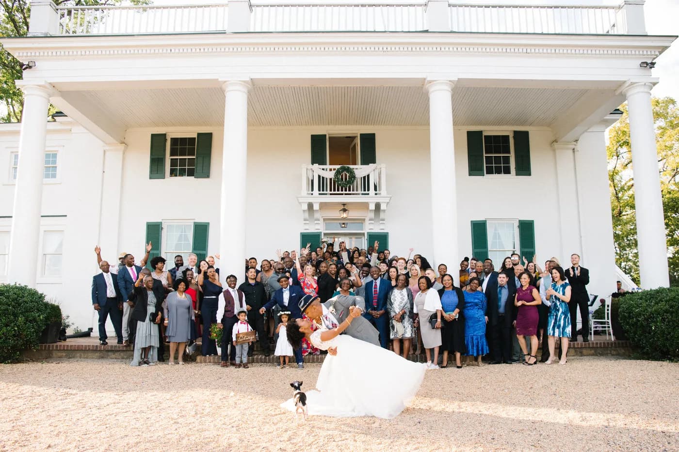 Bride and groom dip kiss before cheering wedding guests at Rixey Manor's white-columned historic estate