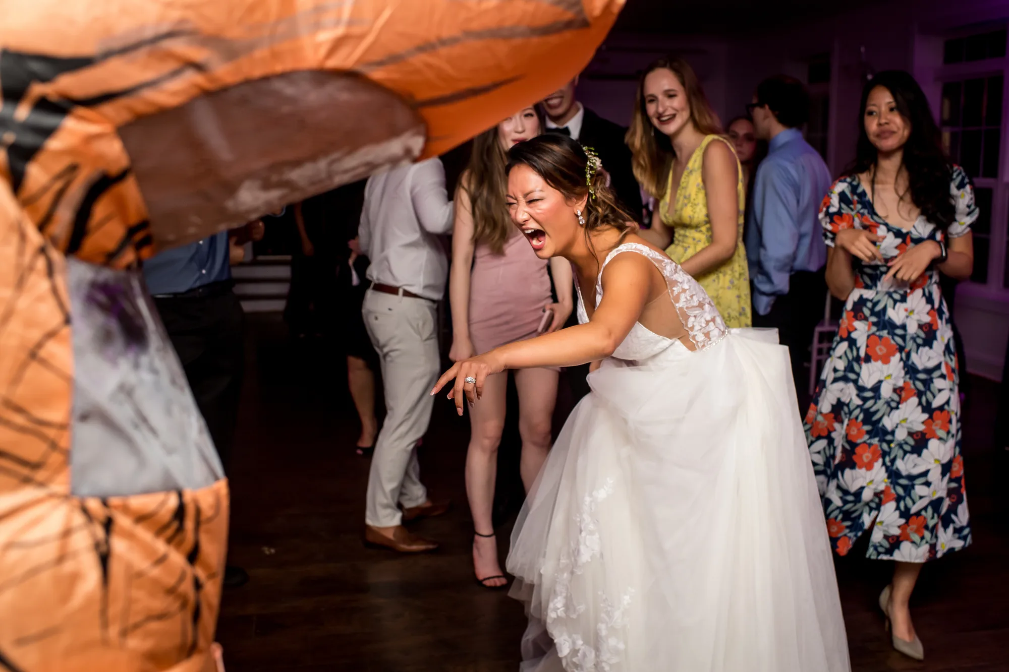 Bride laughing joyfully on the dance floor surrounded by guests at wedding reception