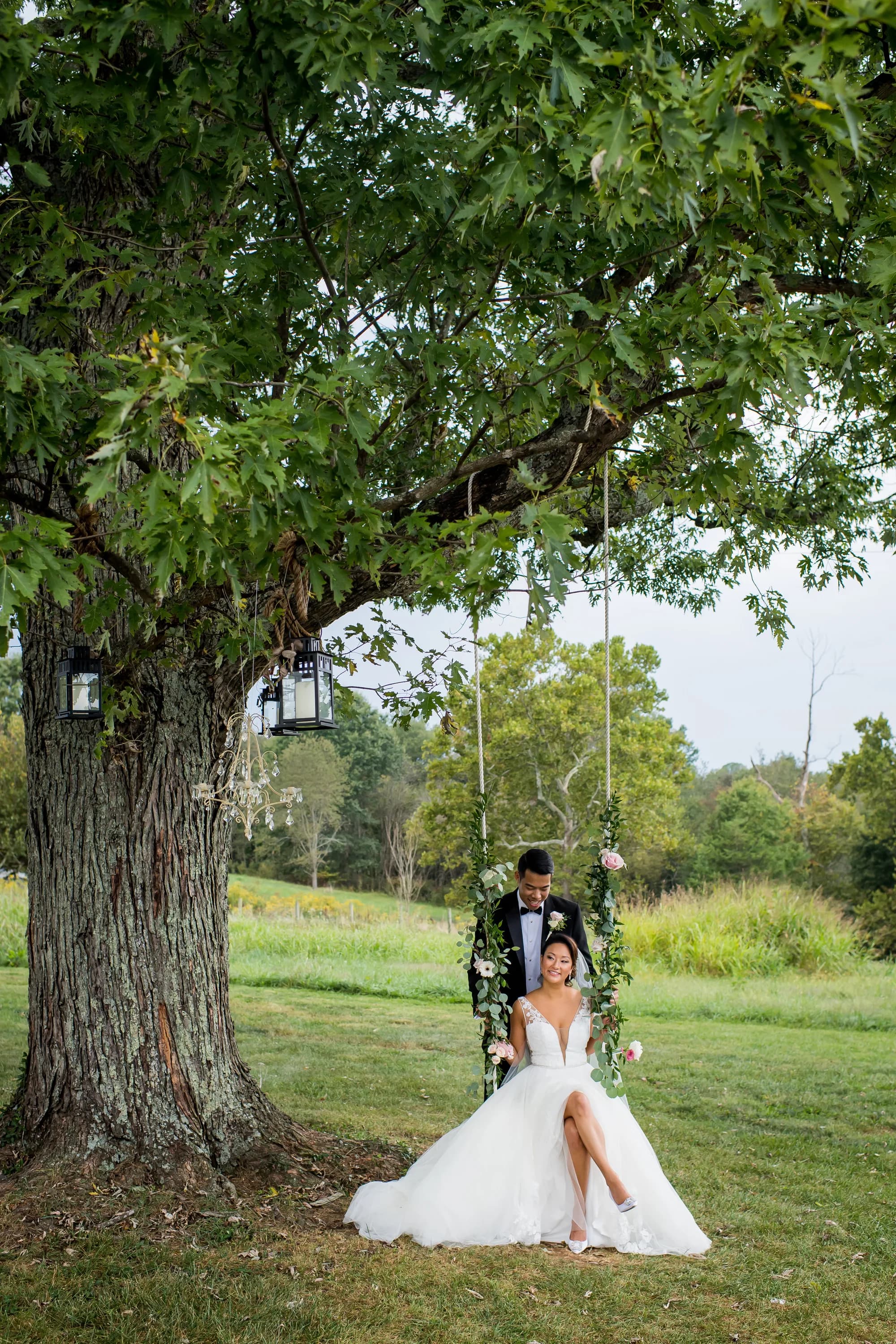 Bride and groom on swing beneath large tree in rural Virginia field setting