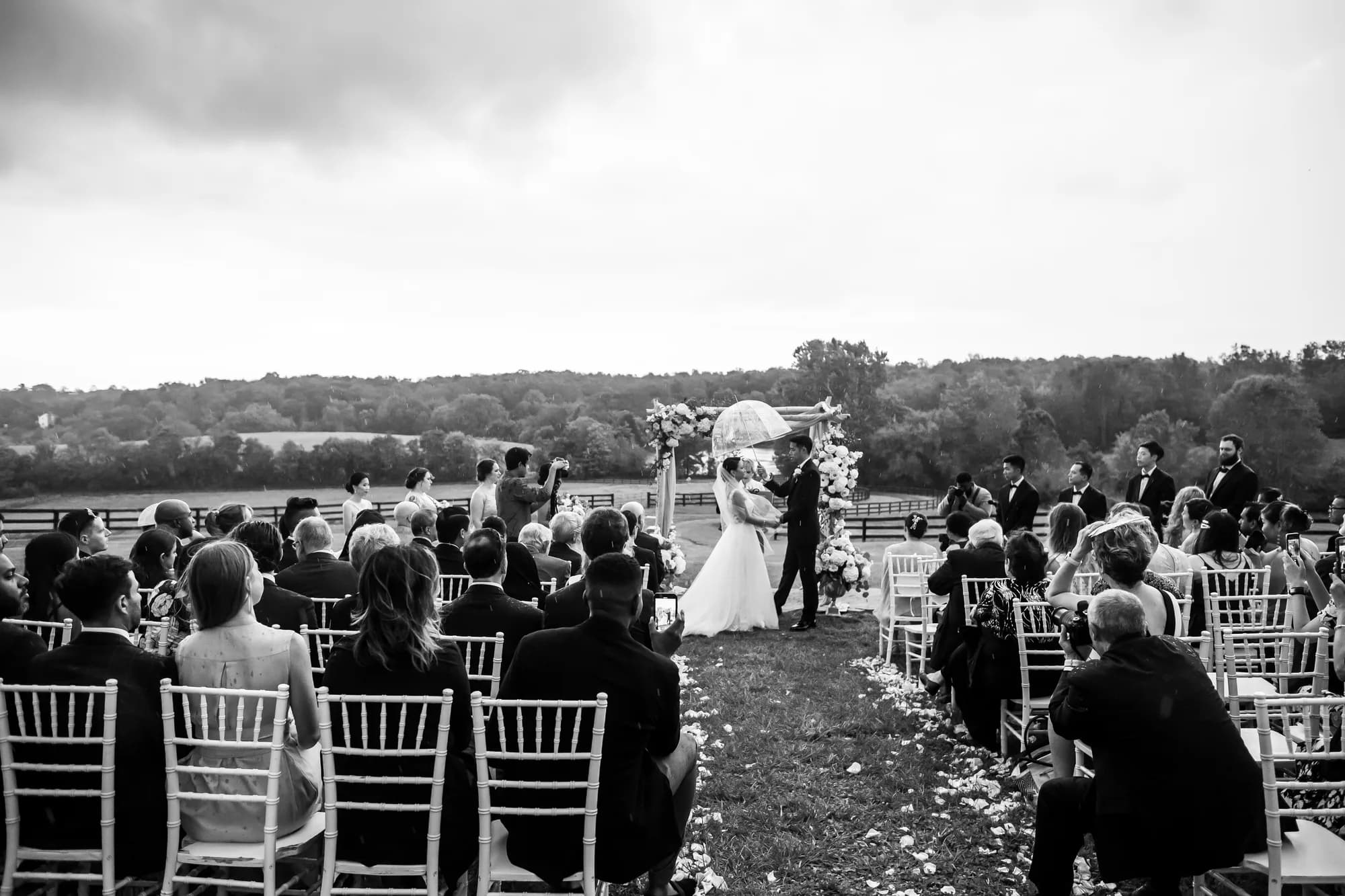 Outdoor wedding ceremony at Rixey Manor with couple at floral arch, rolling Virginia countryside in background
