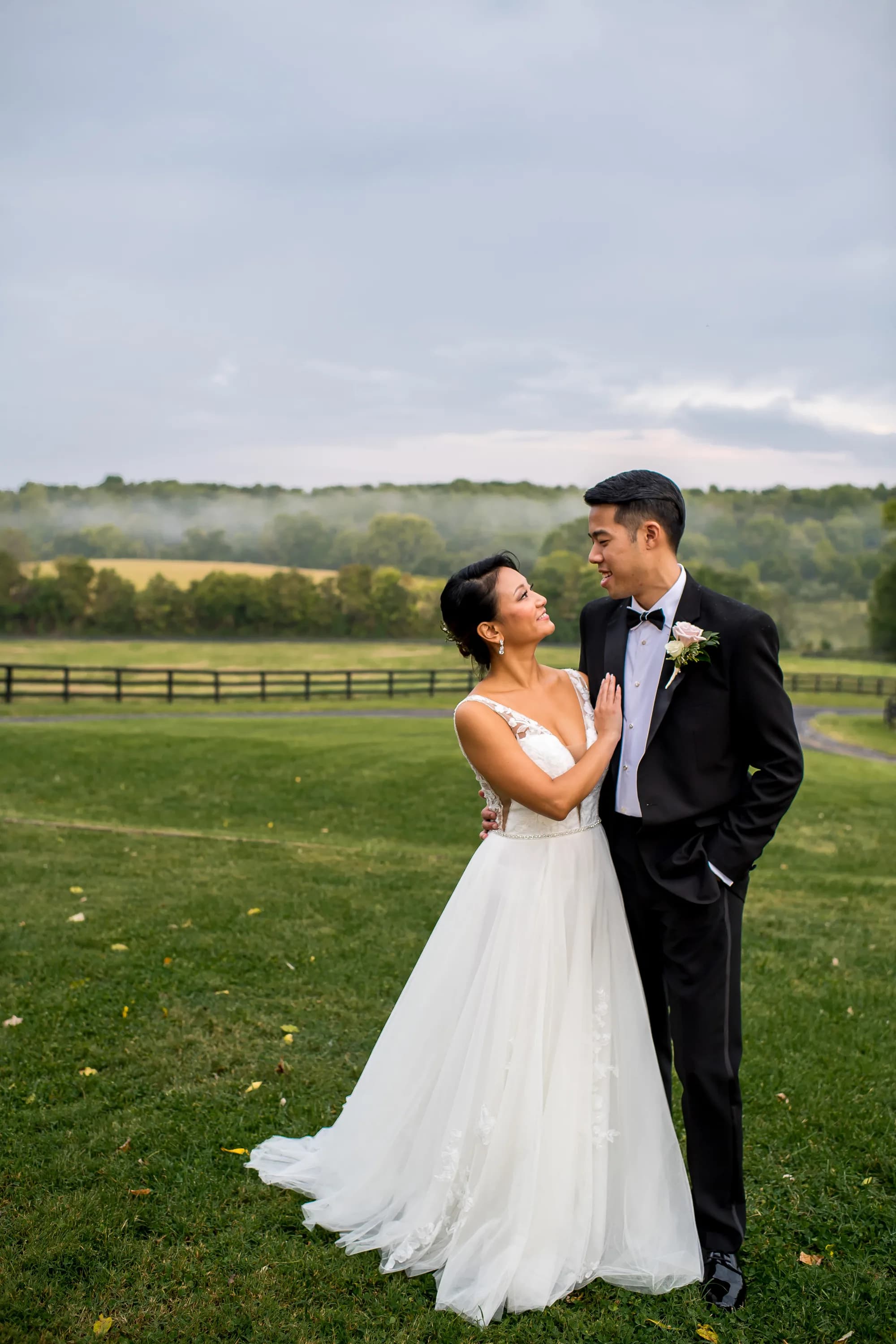 Bride and groom share a loving gaze on Rixey Manor's rolling green grounds with misty pastoral backdrop