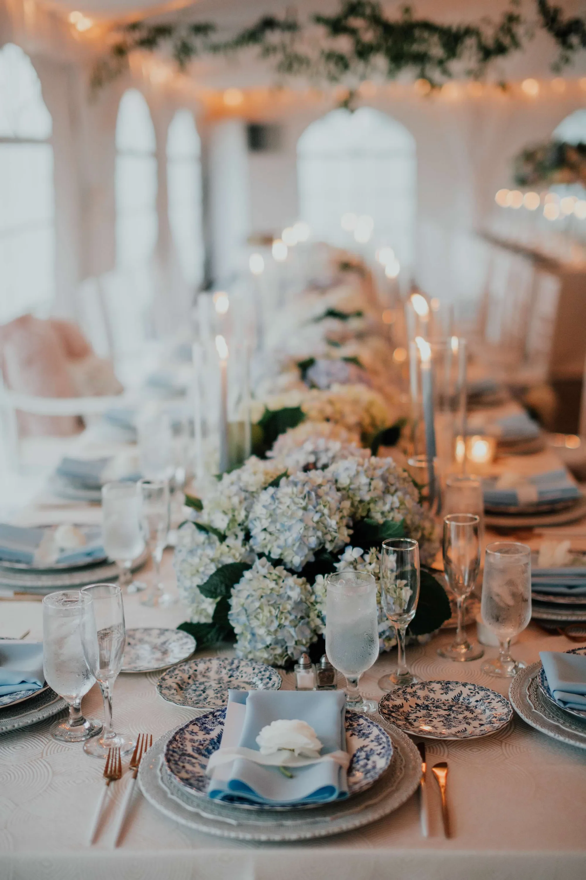 Elegant wedding table setting with white hydrangea centerpiece, place settings, and candlelight