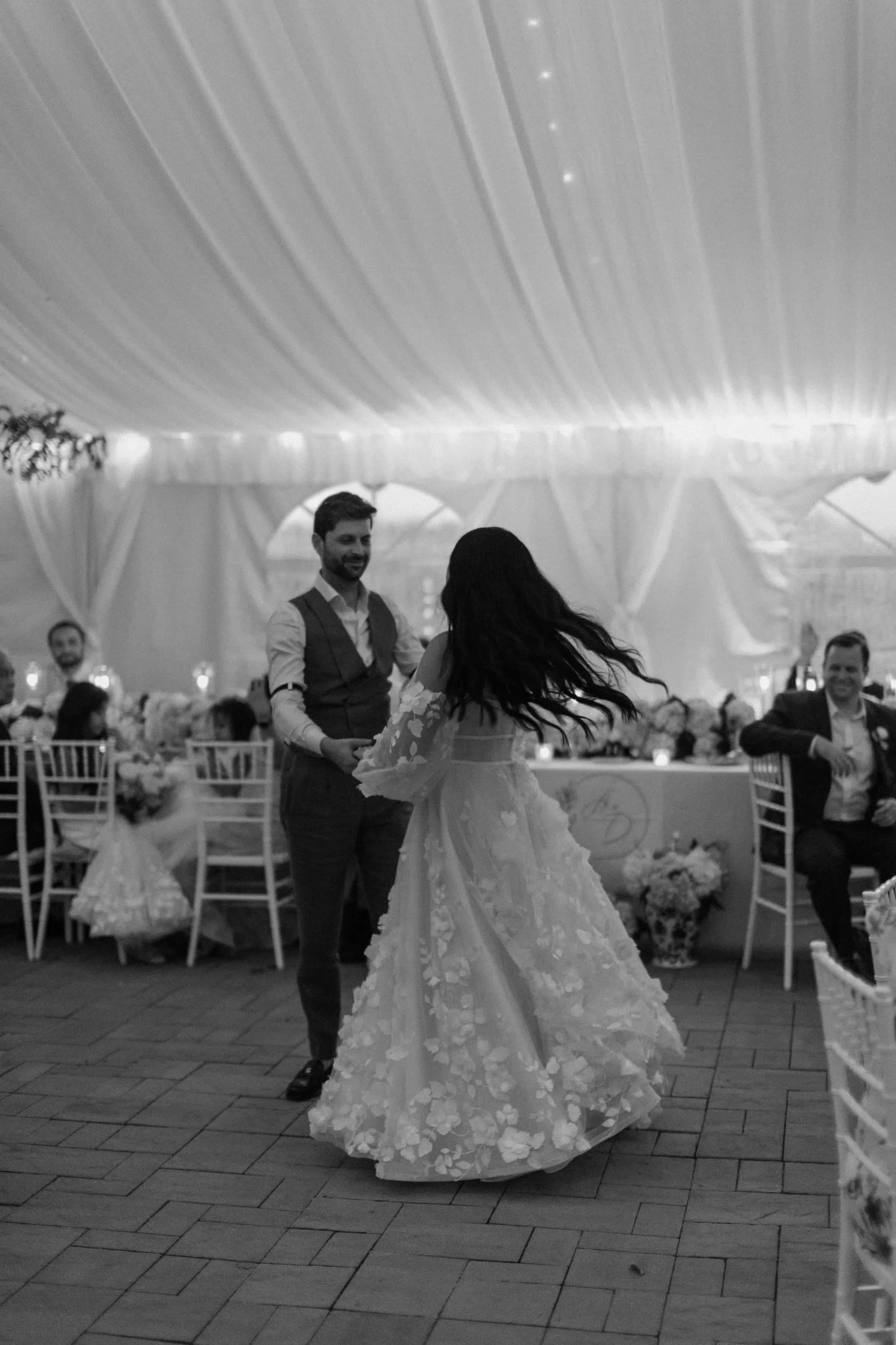 Bride and groom share first dance under draped tent at Rixey Manor reception as guests look on