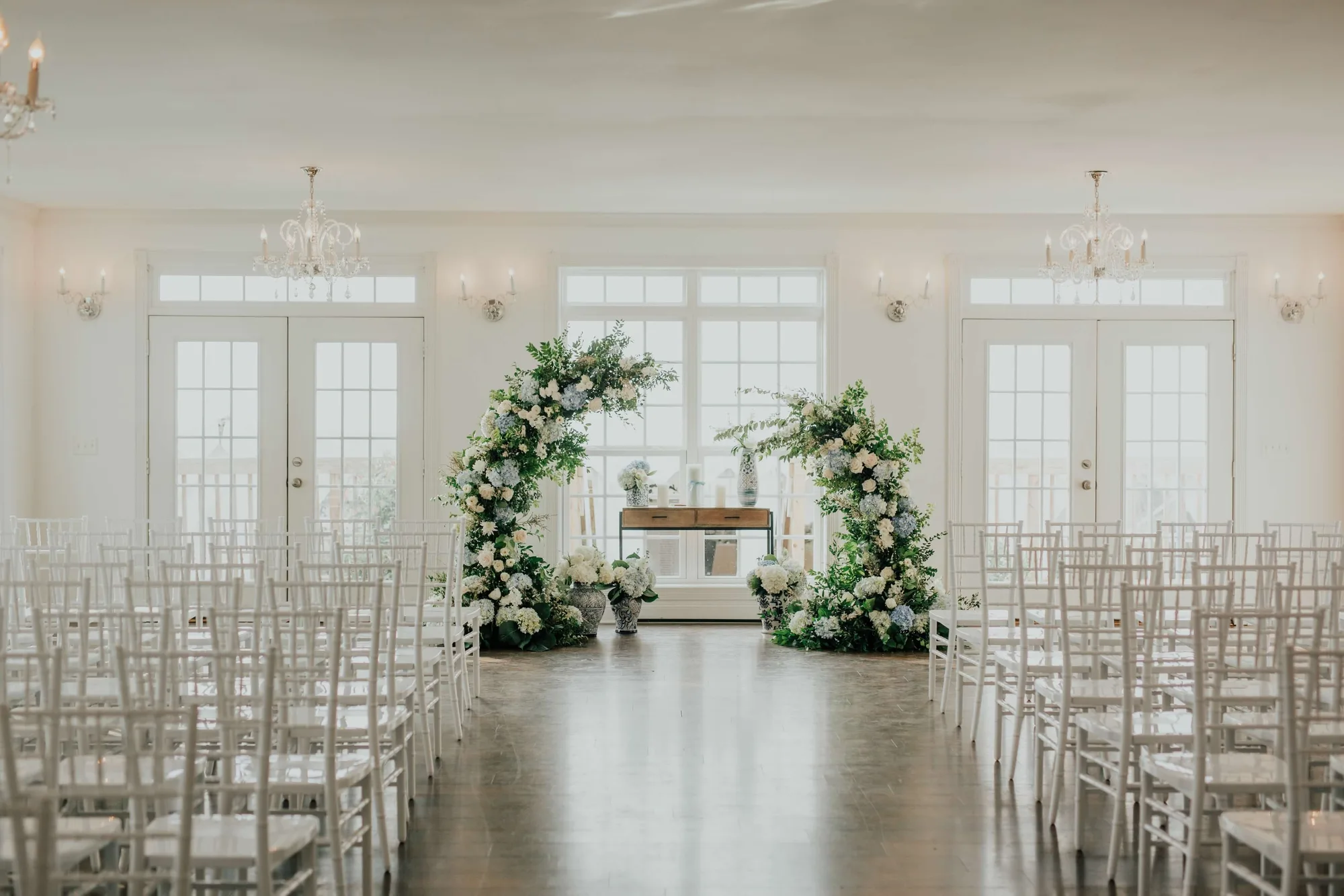 Elegant ceremony space at Rixey Manor with floral arch, white chiavari chairs, and French doors