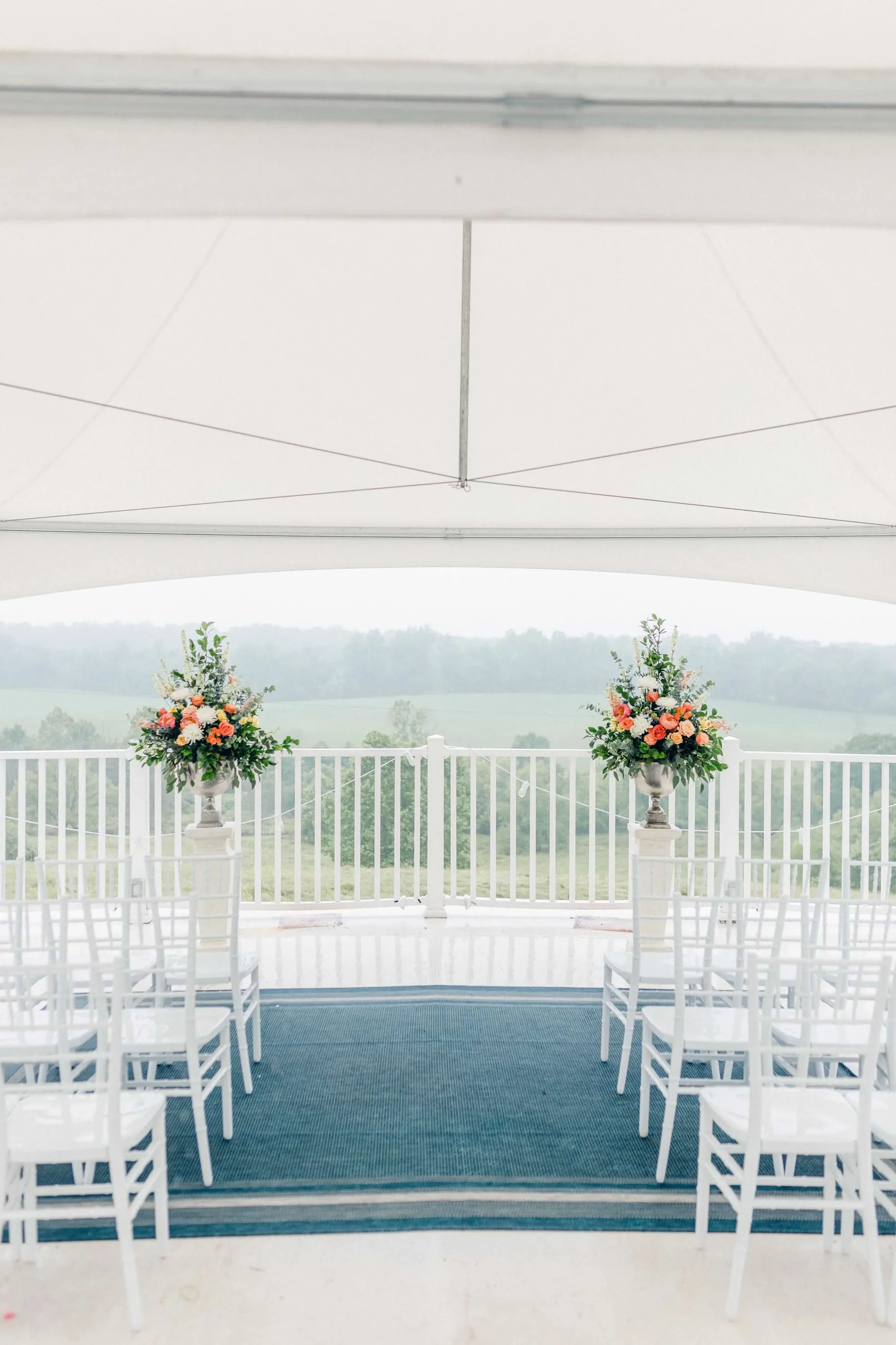 Elegant ceremony setup under terrace tent at Rixey Manor with floral urns and sweeping Virginia countryside views