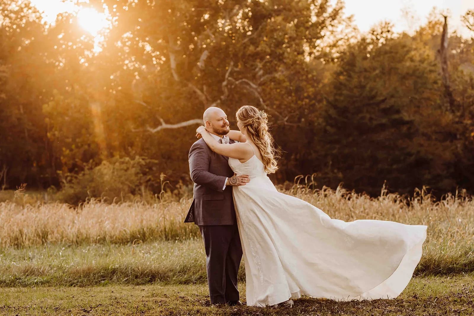 Bride and groom embrace in golden hour light on Rixey Manor's pastoral meadow grounds, gown flowing in the breeze