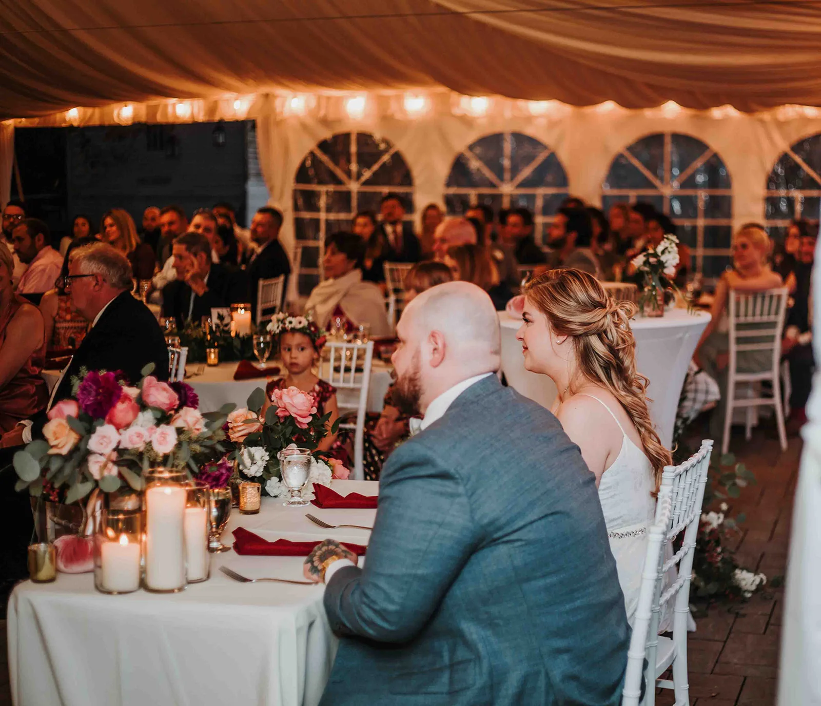 Bride and groom share an intimate moment at sweetheart table inside Rixey Manor's candlelit reception tent