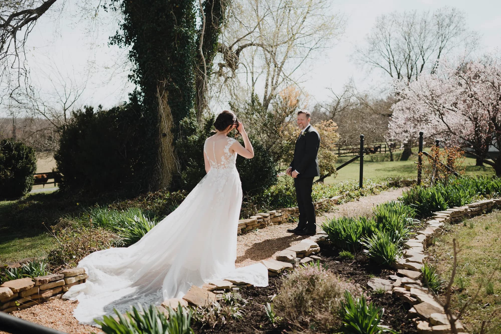 Bride and groom share a first look moment on a stone garden path at Rixey Manor in spring bloom