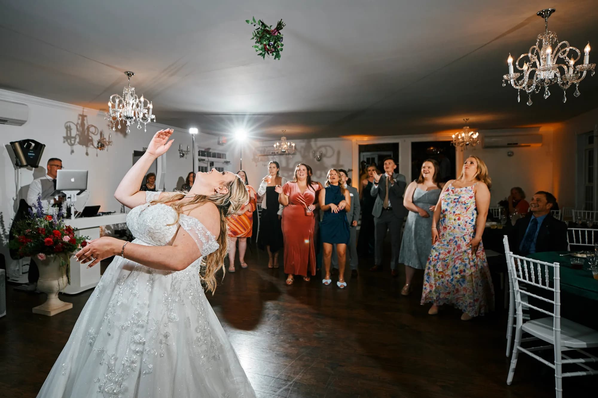 Bride tosses bouquet to excited guests under crystal chandeliers in the Rixey Manor ballroom