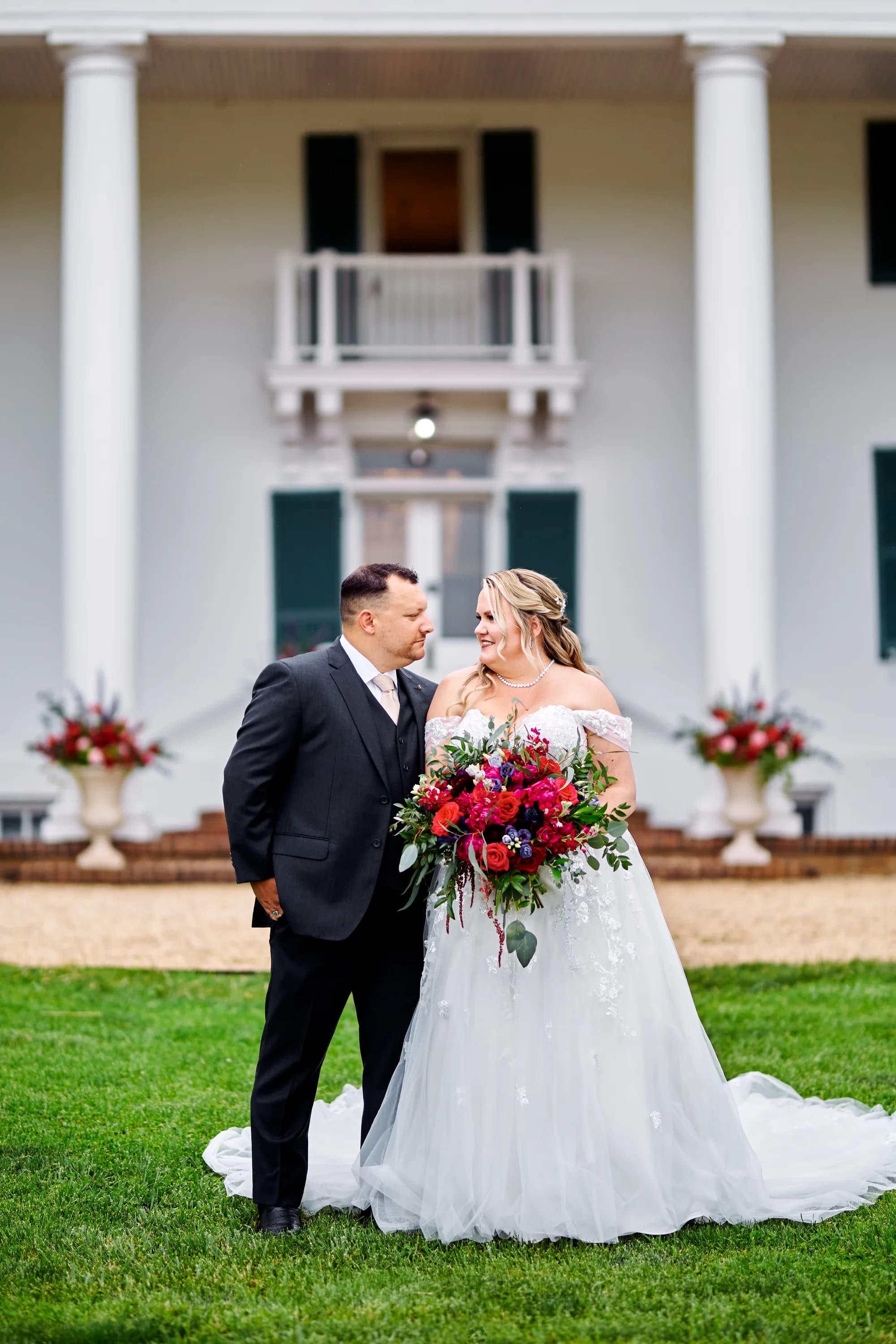 Bride and groom share a tender moment on the lawn before Rixey Manor's white-columned facade