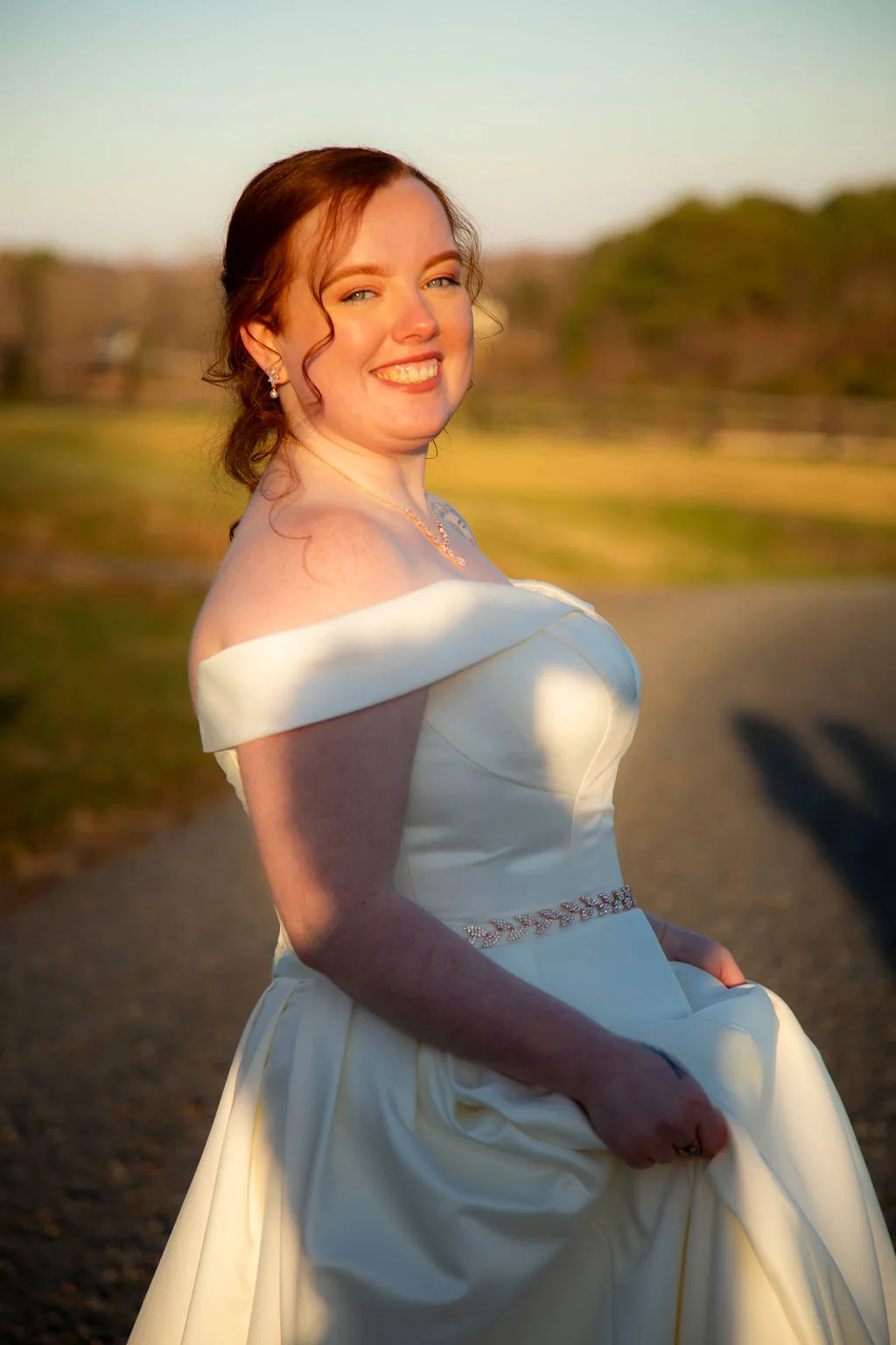 Radiant bride in off-shoulder gown smiling in golden hour light on Rixey Manor grounds