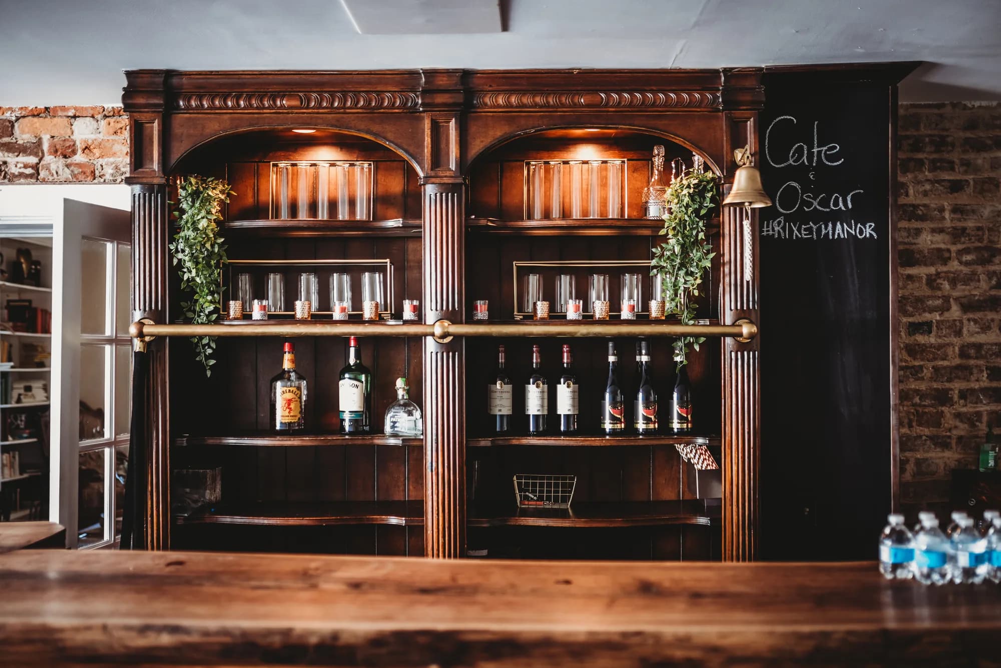 Dark wood bar shelf with liquor bottles and glassware at Cafe Oscar inside Rixey Manor