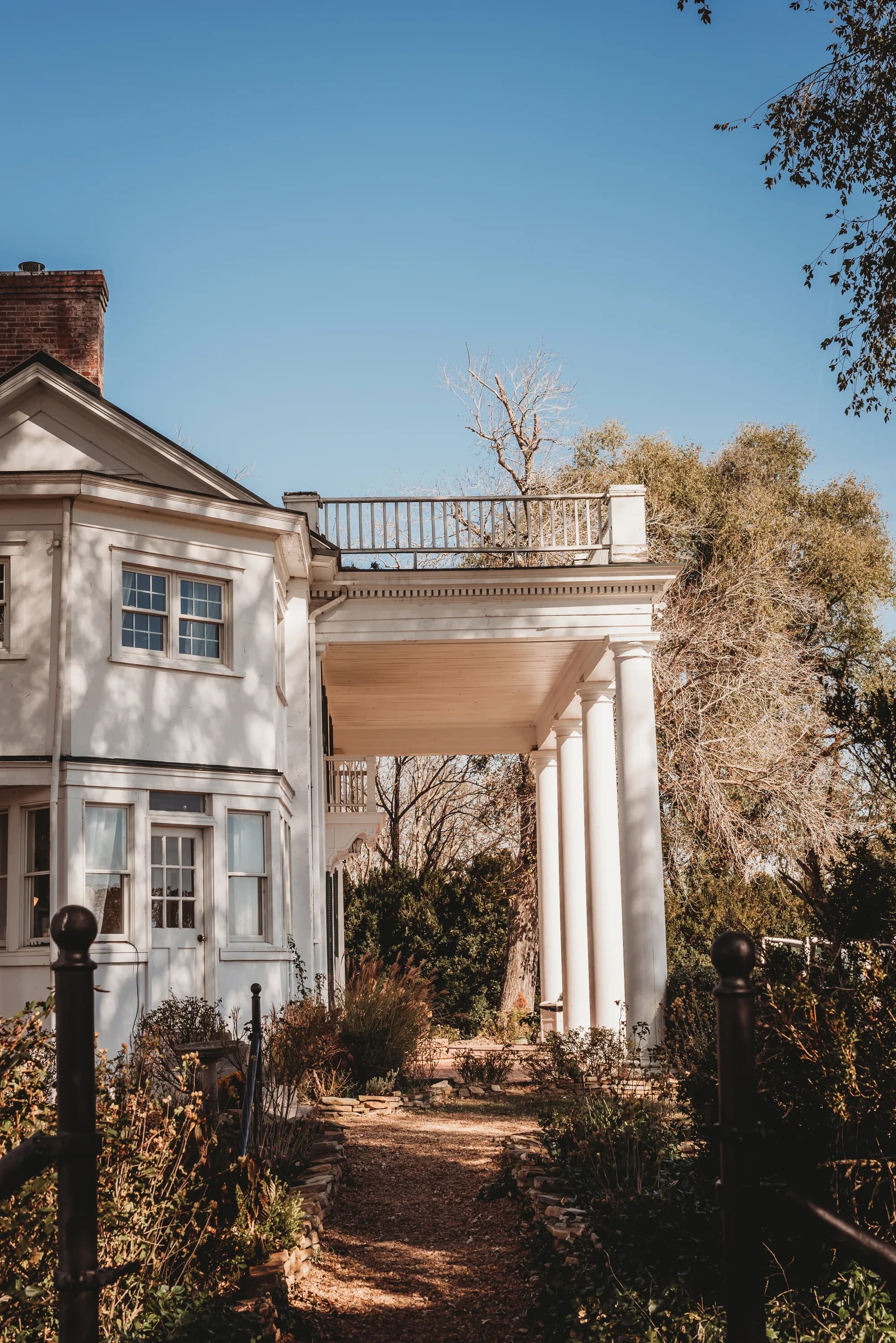 White colonial manor with grand columns and rooftop balcony surrounded by autumn gardens at Rixey Manor