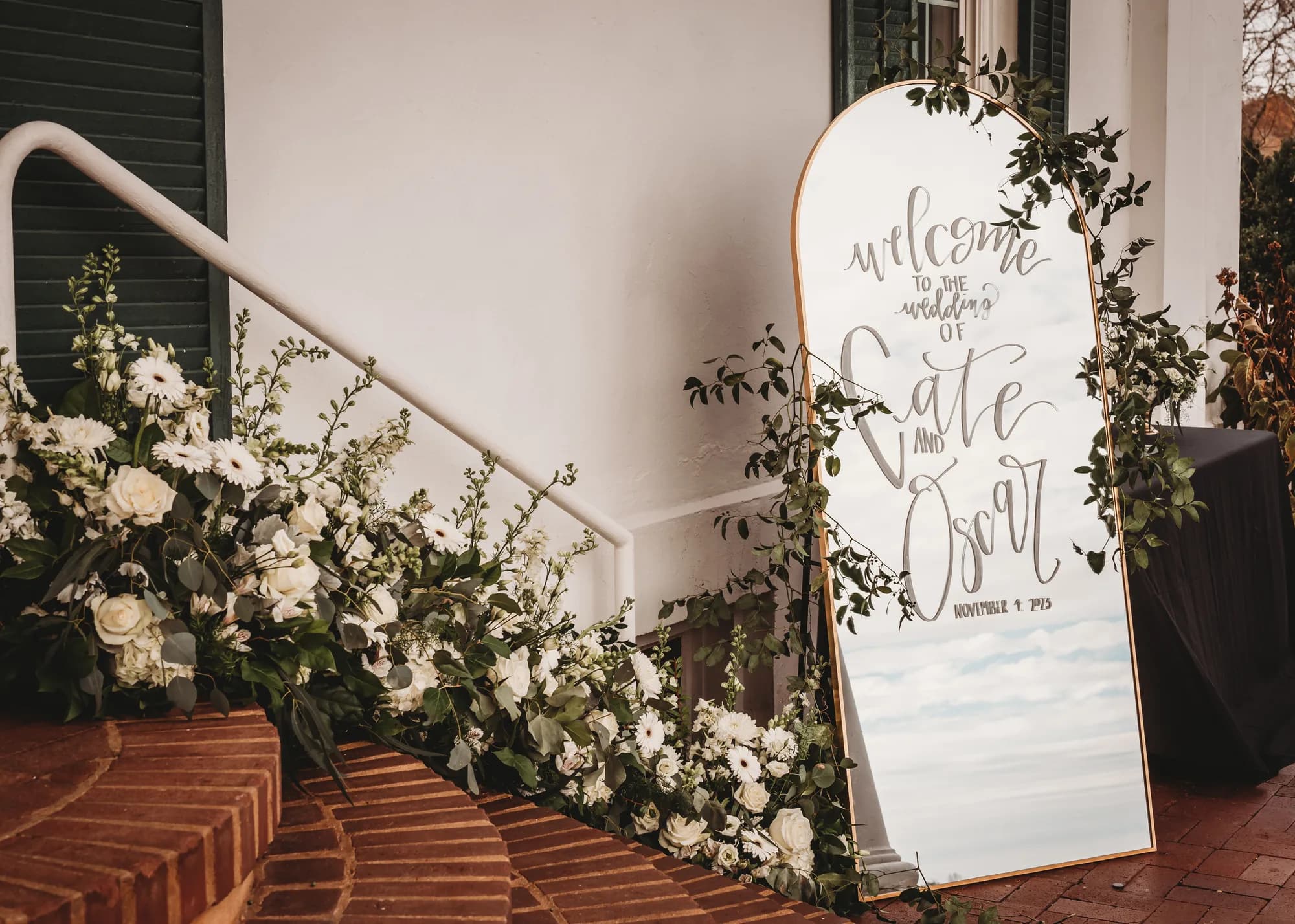 Gold arch welcome mirror and white floral staircase display at Rixey Manor entrance