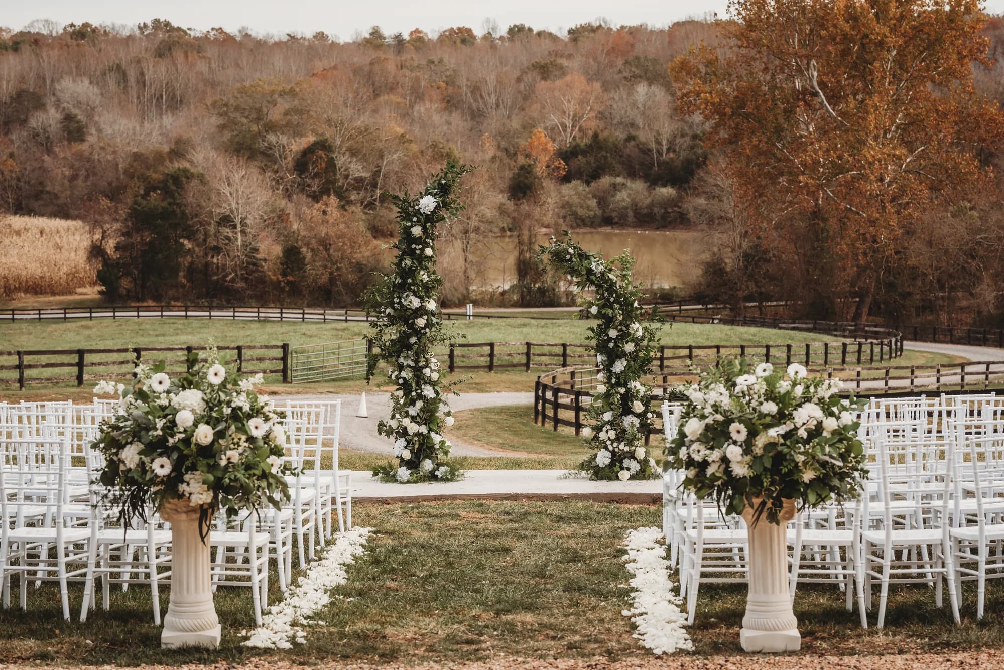 Elegant outdoor ceremony setup with floral arches and white chairs overlooking Rixey Manor's pastoral Virginia countryside