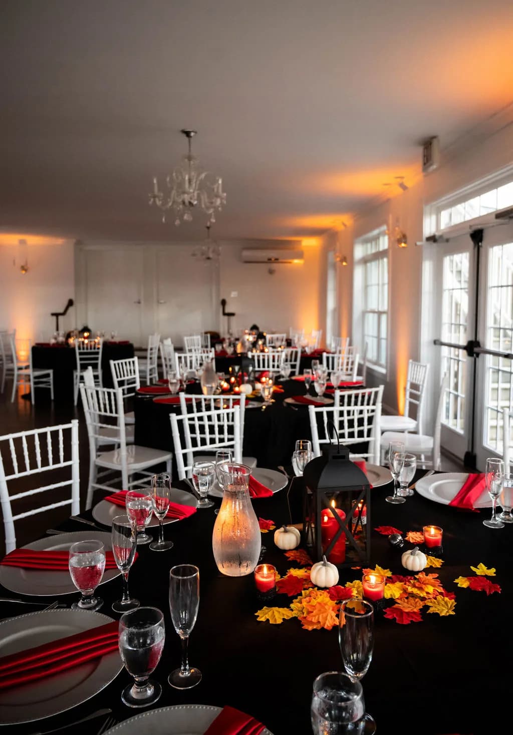 Fall reception tablescape at Rixey Manor with black linens, lanterns, mini pumpkins, and autumn leaves under warm uplighting