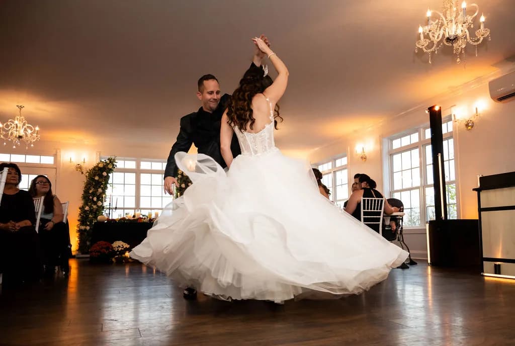 Bride and groom share first dance under crystal chandeliers in the Rixey Manor ballroom, gown swirling mid-spin