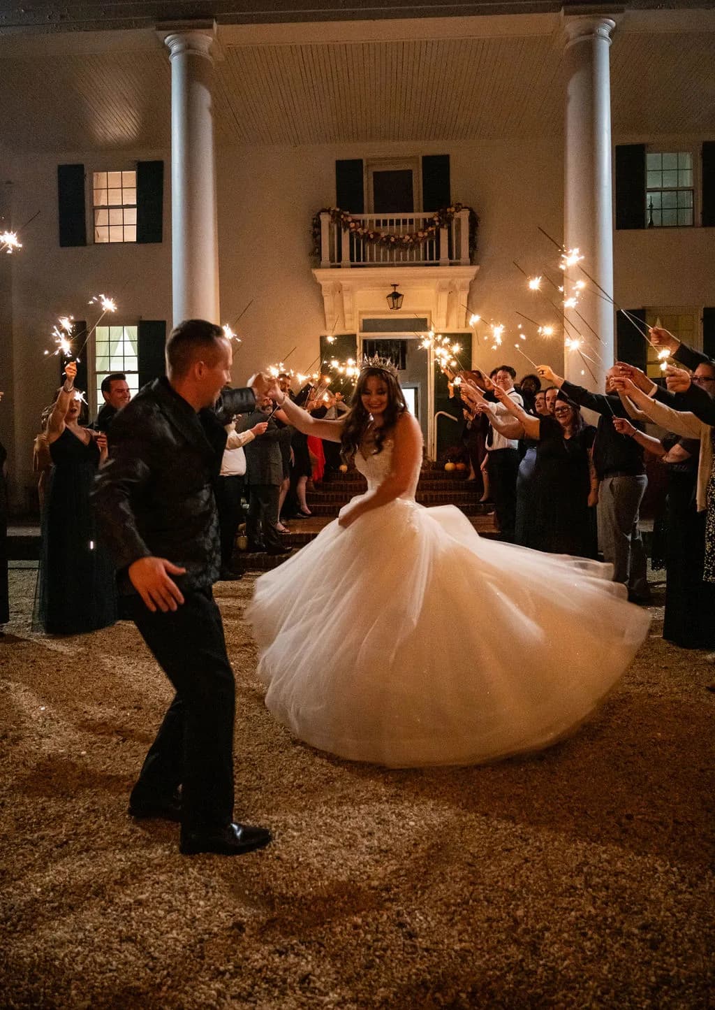 Bride twirls in ballgown during sparkler exit at Rixey Manor's columned facade at night
