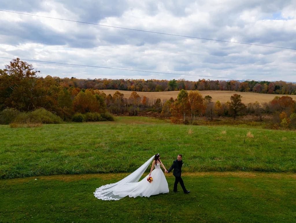 Bride and groom walk hand-in-hand across sweeping autumn fields at Rixey Manor, Virginia