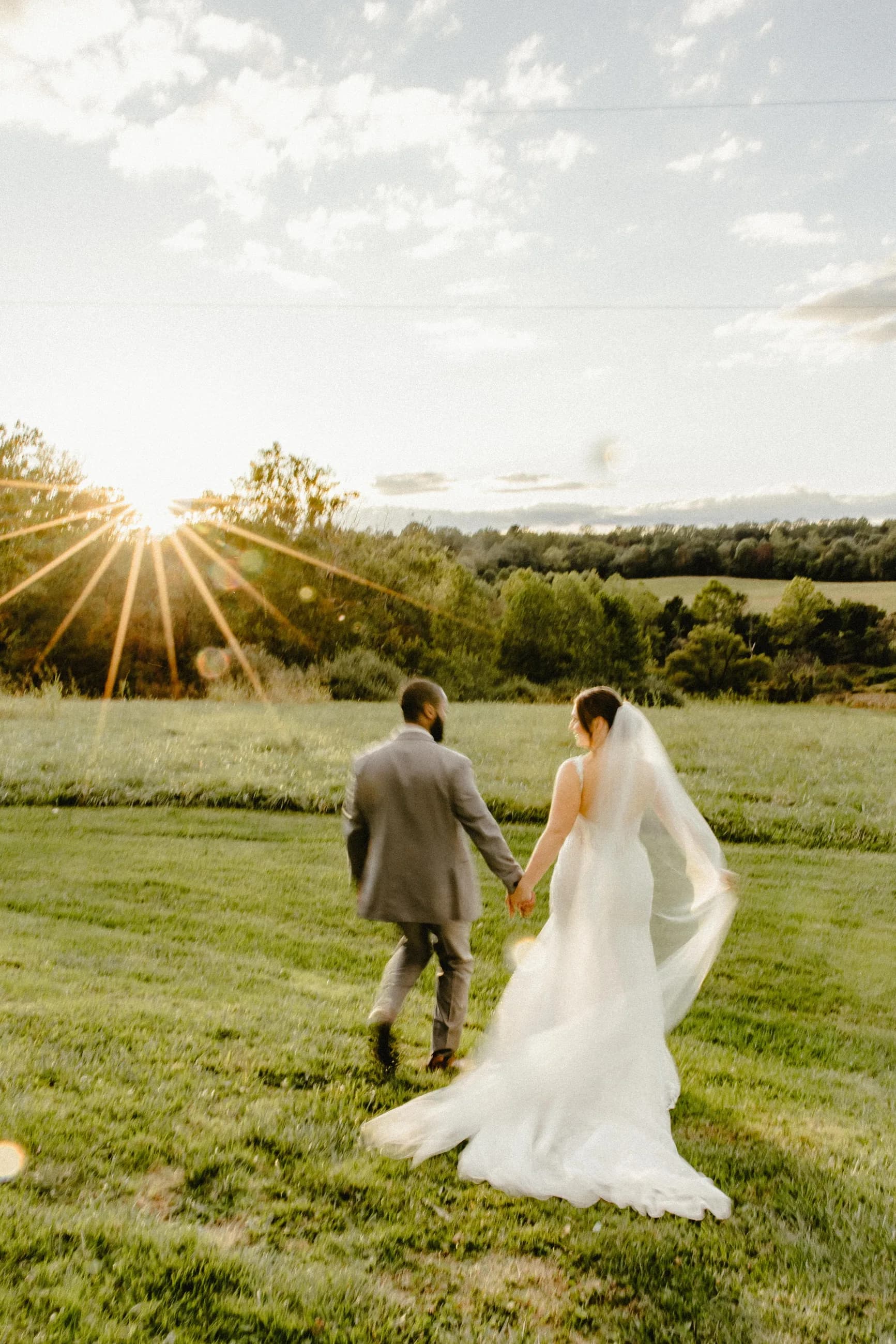 Bride and groom walk hand-in-hand toward golden sunset across Rixey Manor's rolling Virginia countryside