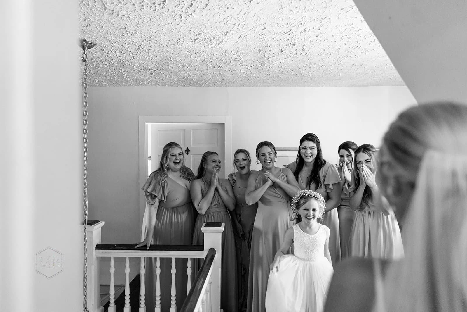 Bridesmaids and flower girl react with joy and tears seeing the bride for the first time on wedding day