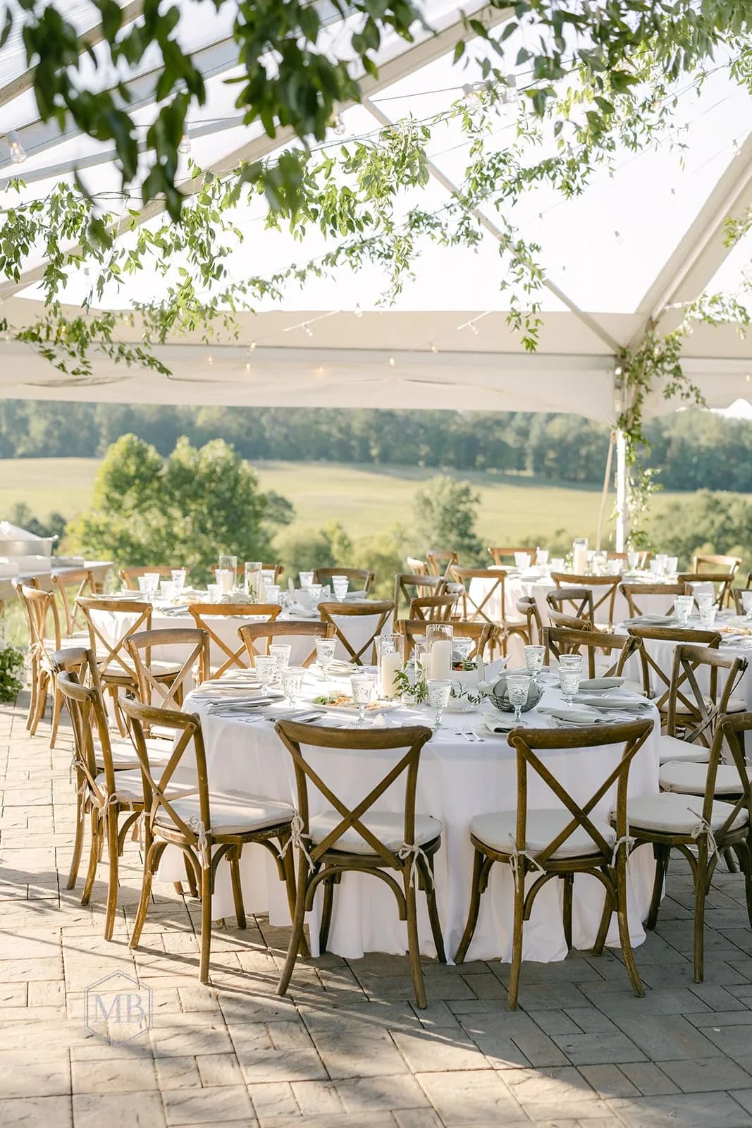 Elegant outdoor reception under glass pavilion with round tables, cross-back chairs, and countryside views at Rixey Manor