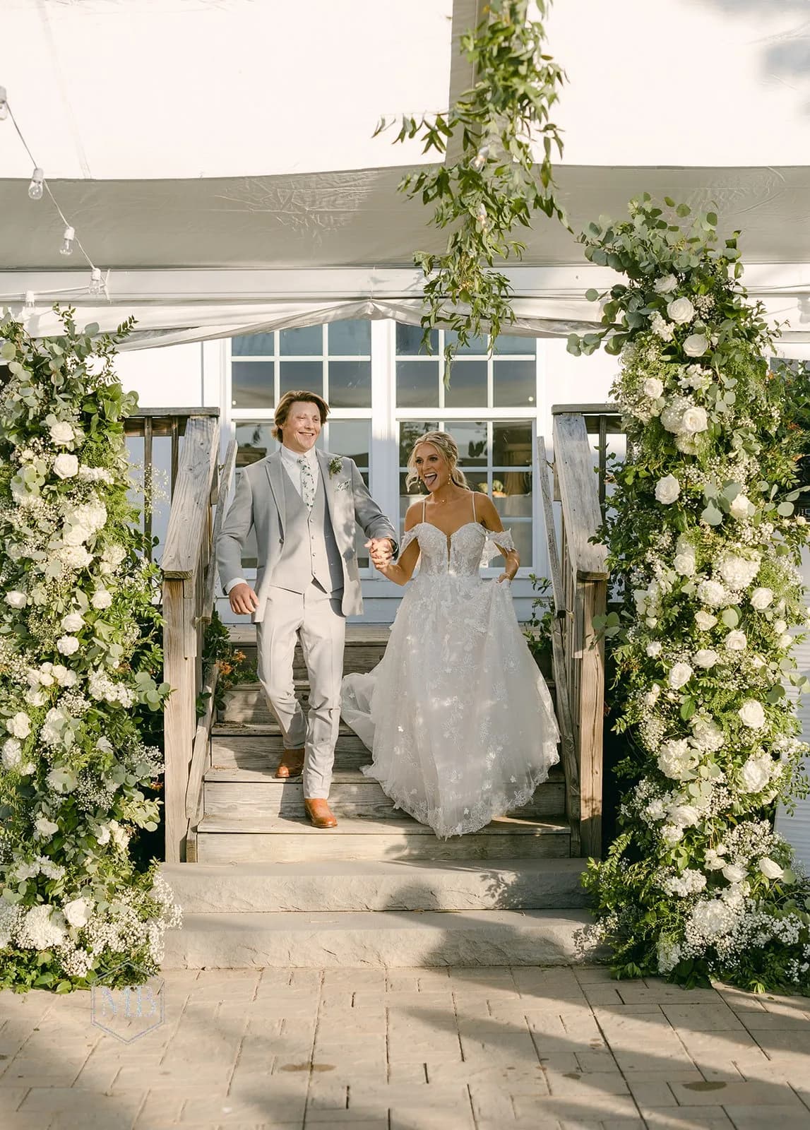 Bride and groom walk through white floral arch at Rixey Manor wedding ceremony