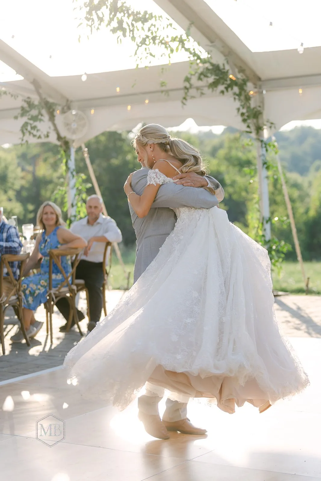 Bride and groom share first dance under a greenery-draped tent at Rixey Manor as guests look on