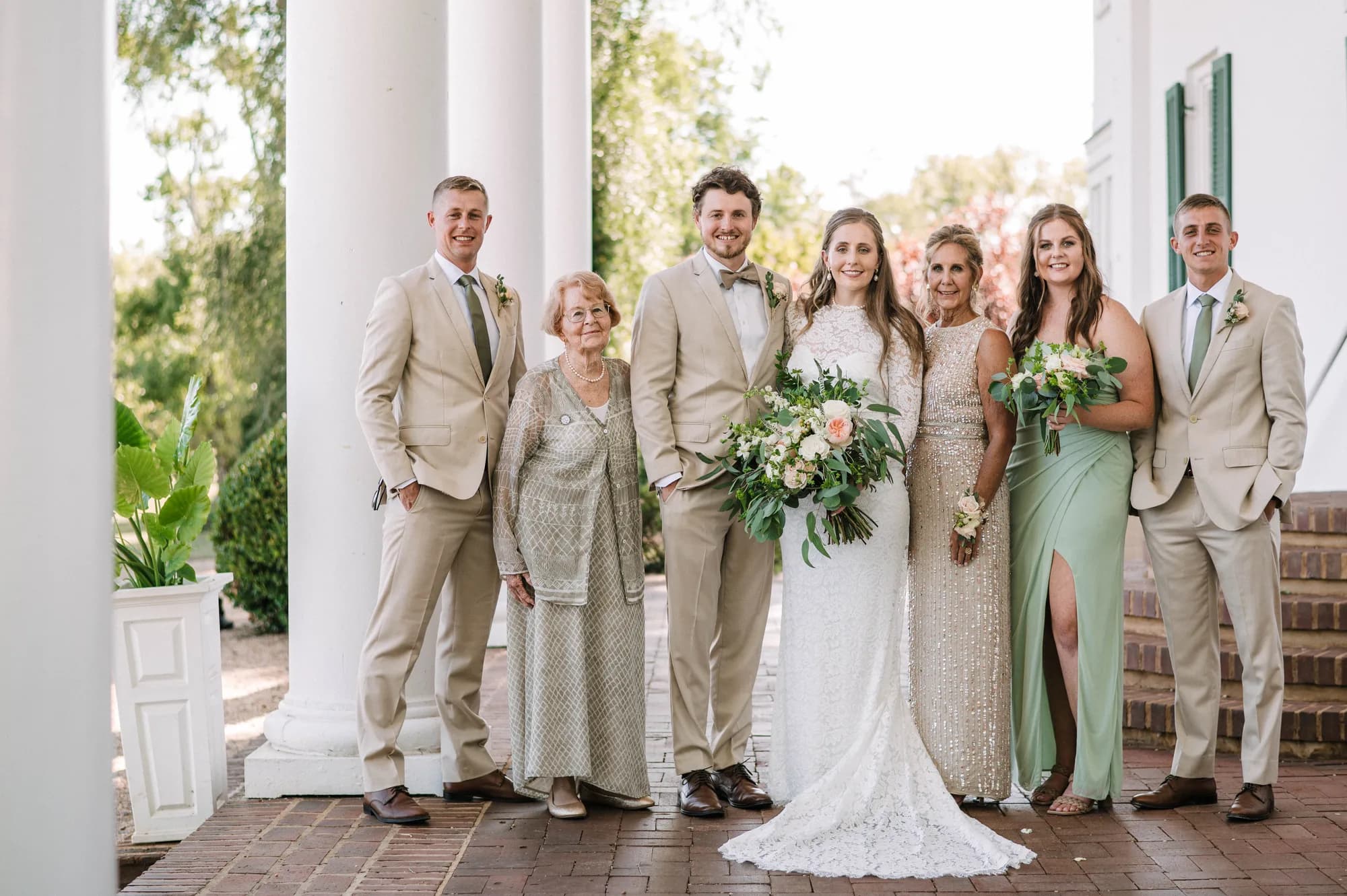 Wedding party family portrait on the columned porch of Rixey Manor in warm neutral and sage tones