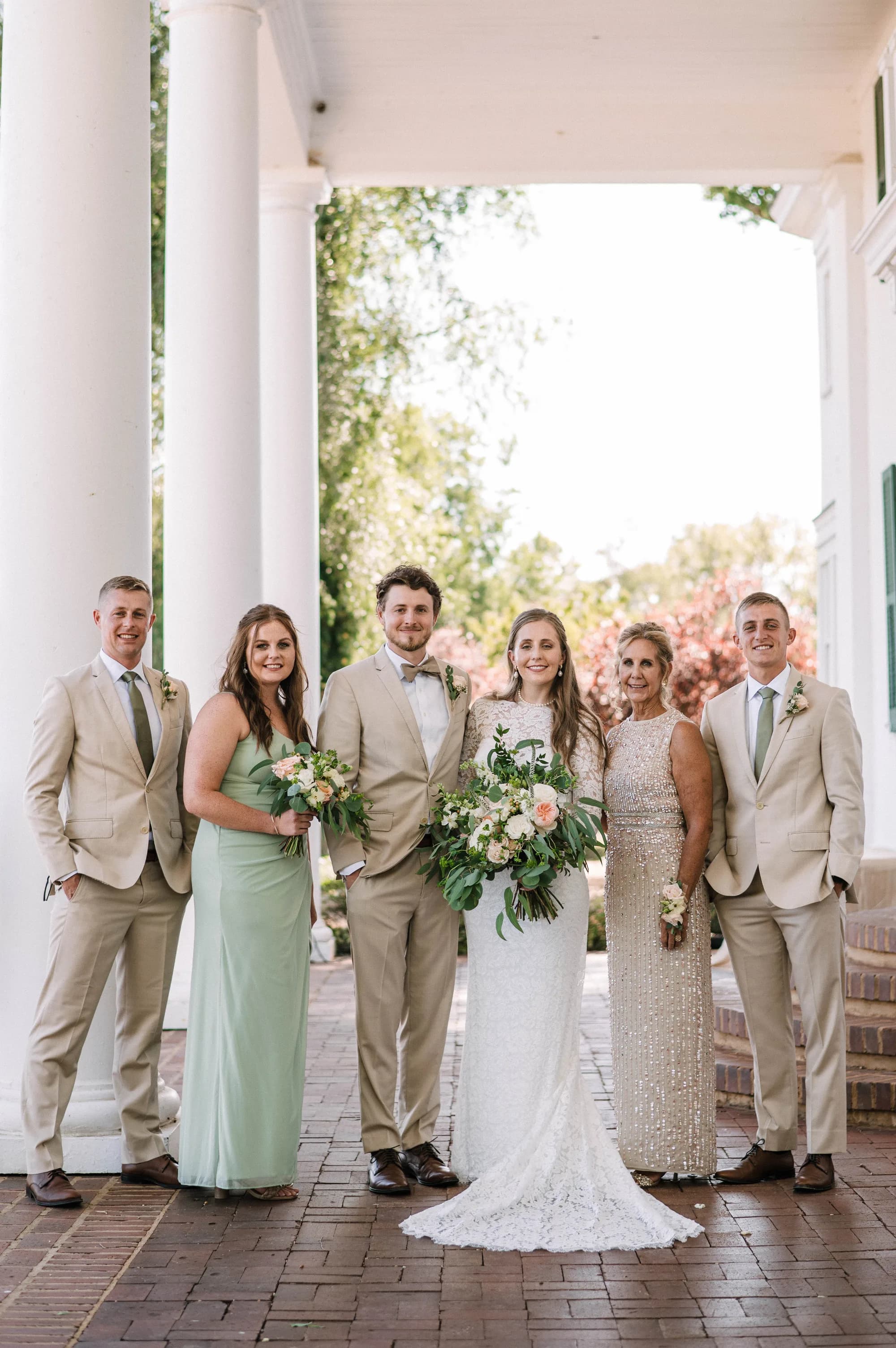 Wedding party family portrait under white columns at Rixey Manor, bride and groom centered with smiling family members