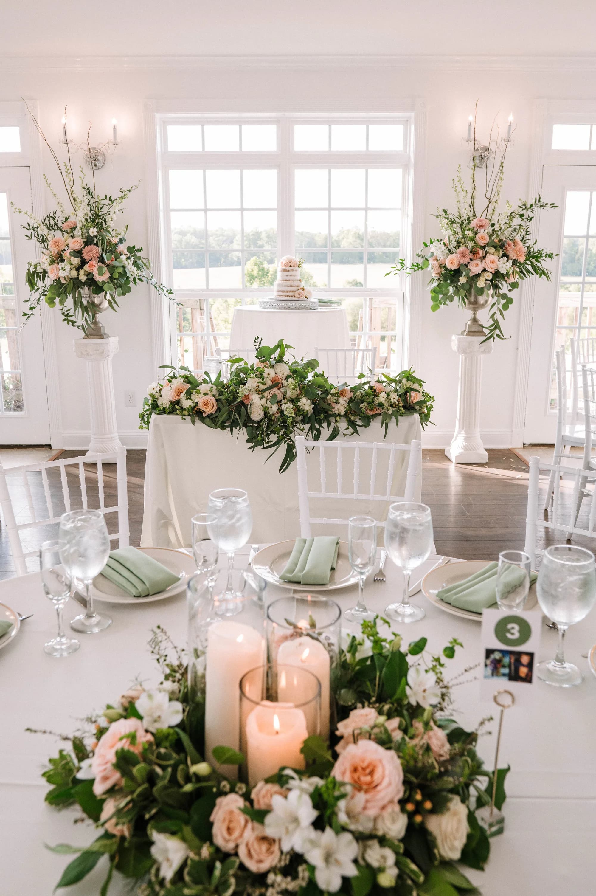 Elegant reception setup at Rixey Manor with blush floral garlands, candles, and sweetheart table framed by large windows
