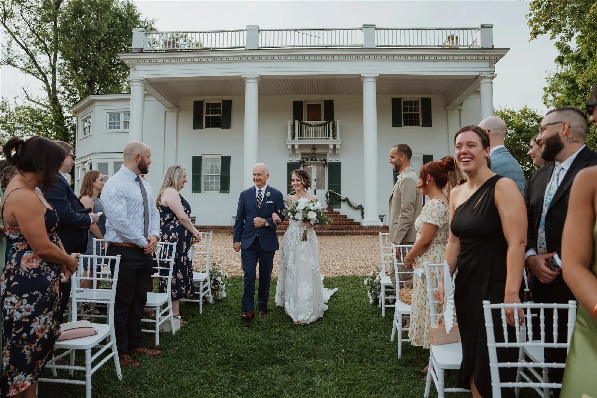 Outdoor wedding ceremony at Rixey Manor with bride and groom exchanging vows before guests seated in white chairs