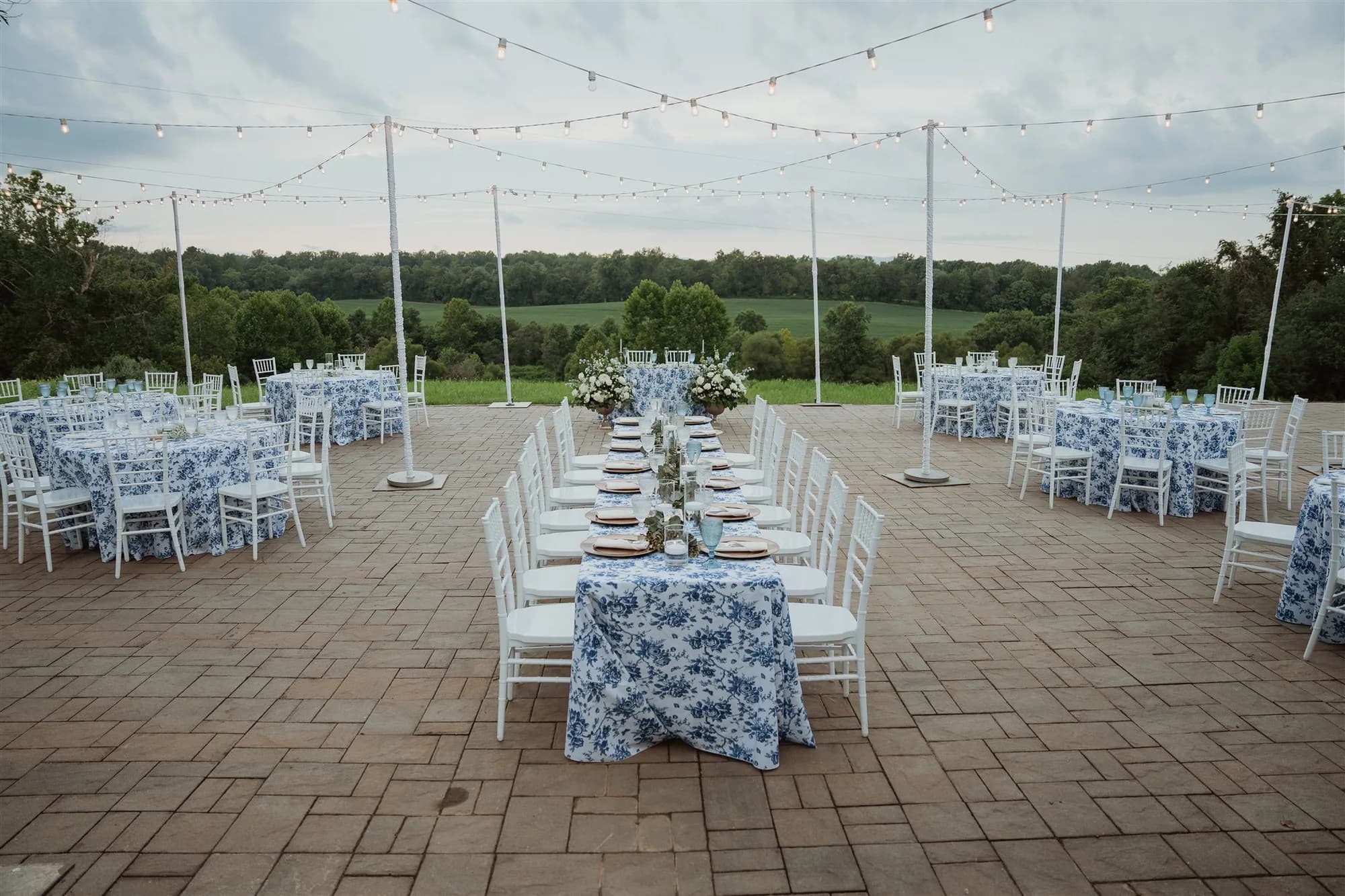 Outdoor reception setup at Rixey Manor with blue floral linens, string lights, and rolling Virginia countryside views